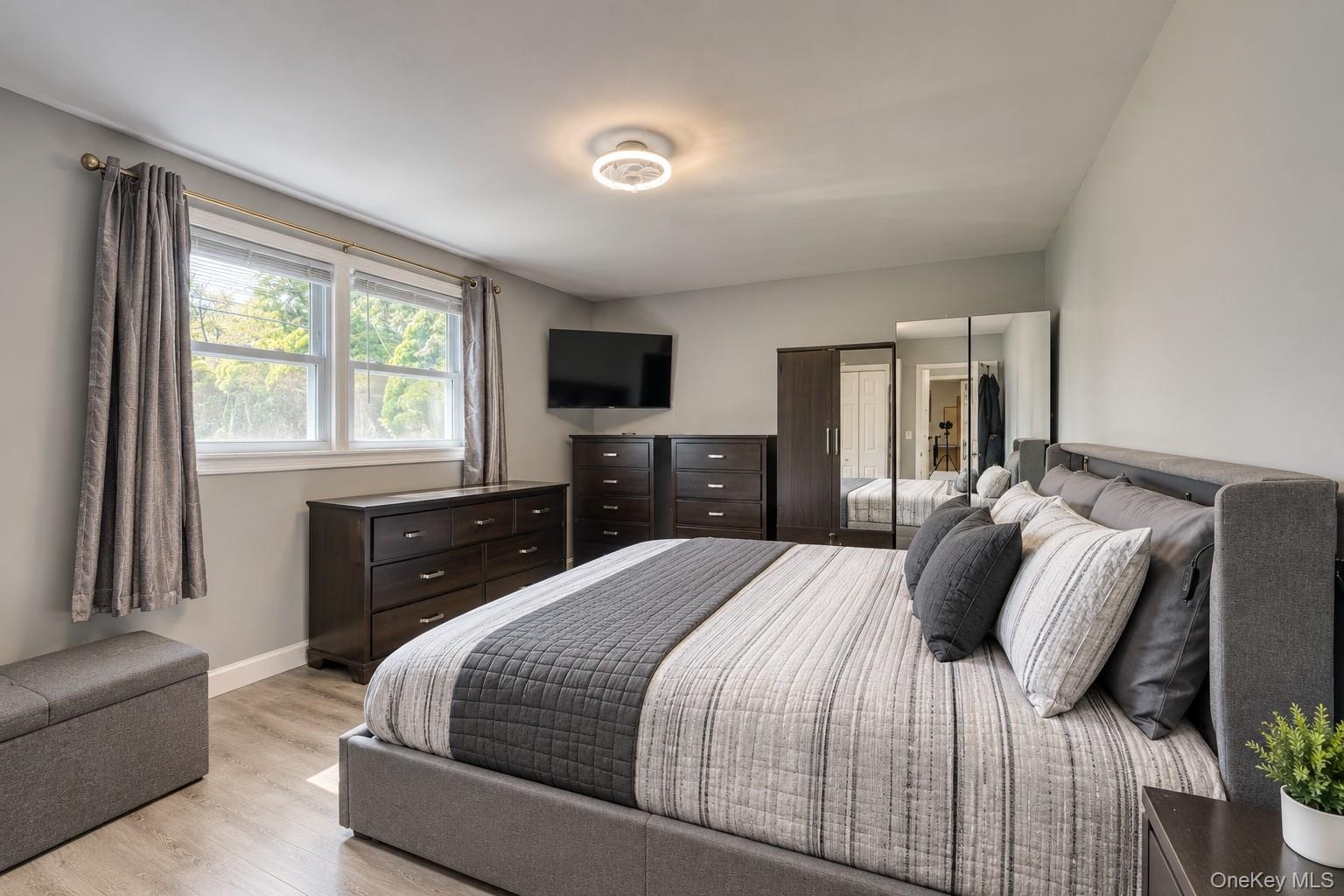 Elegant and spacious bedroom showcasing a modern design with clean lines and neutral tones. The room features a large upholstered bed with coordinated