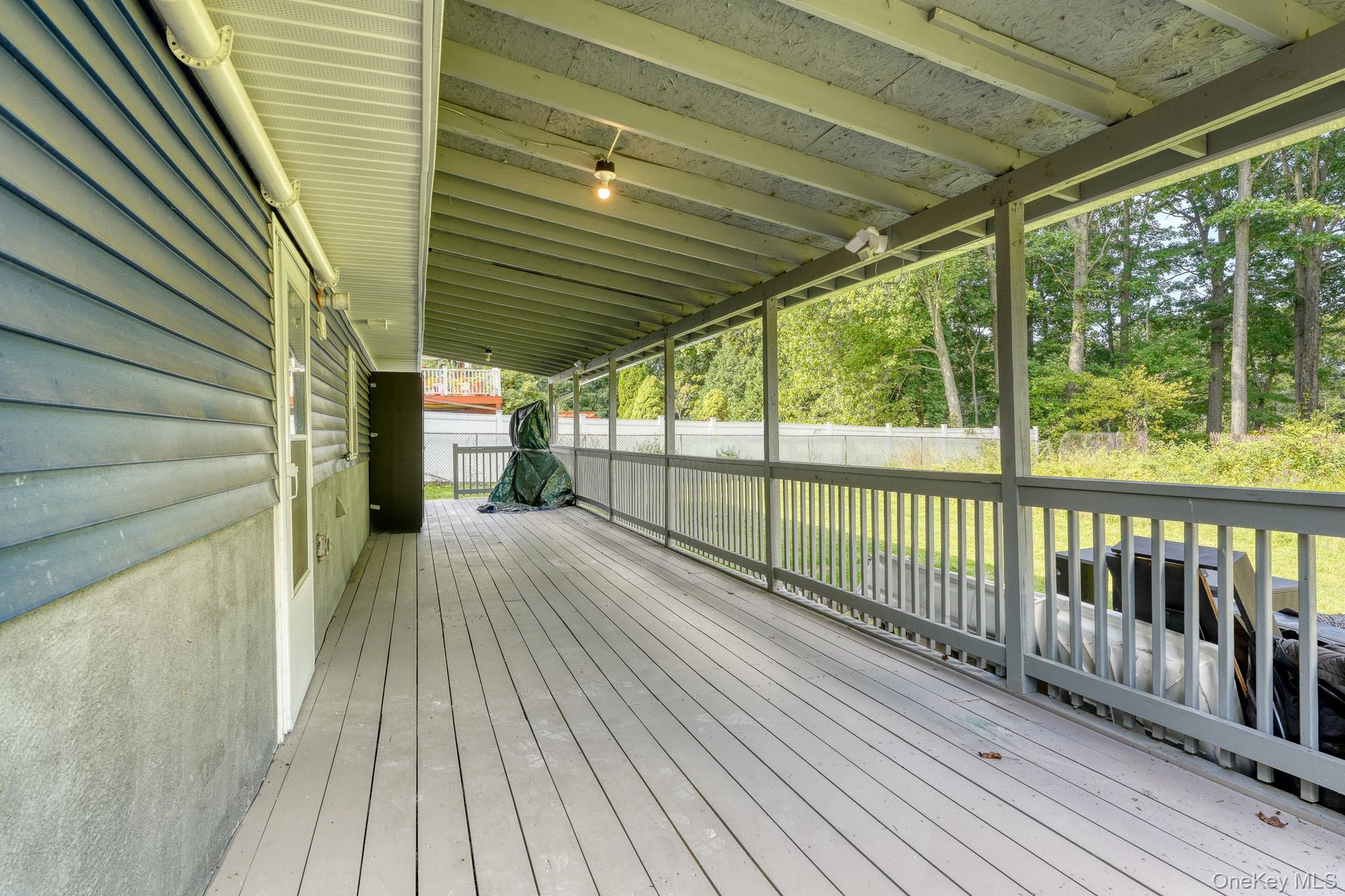 Spacious rear porch featuring a durable wood deck and full overhead coverage for year-round use. The design includes blue siding, white trim, and open