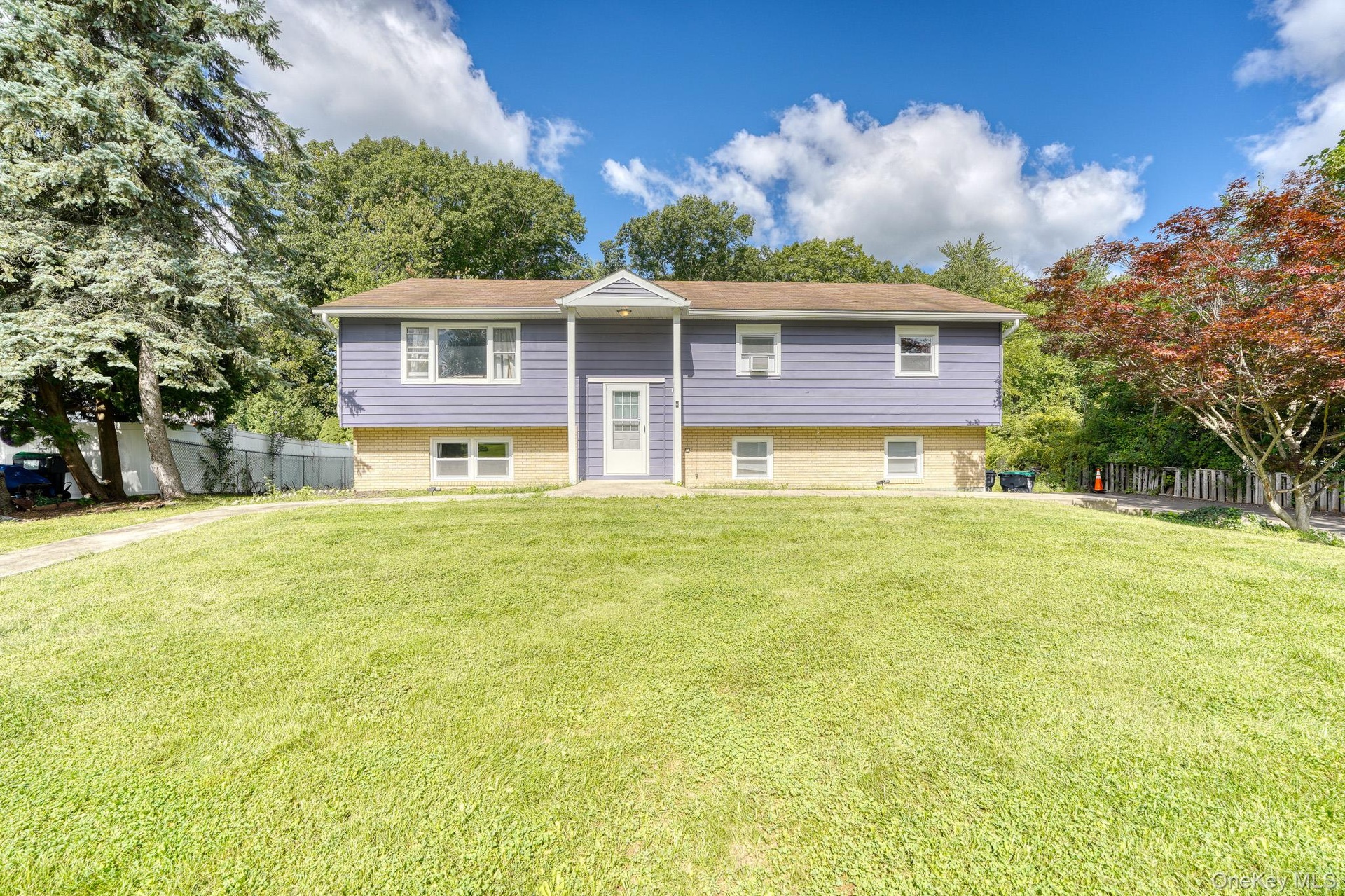 Beautiful split-level home with a modern purple exterior and light brick foundation, set on a spacious, well-manicured lawn. The symmetrical façade fe