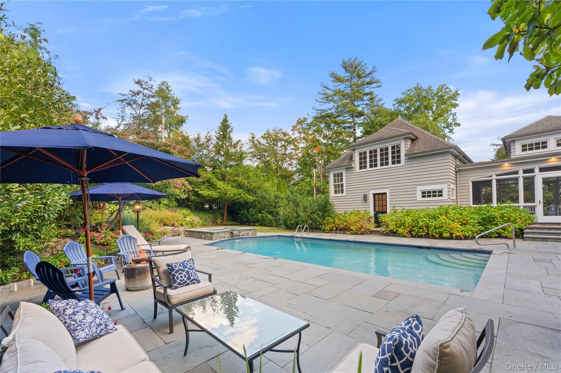 Beautifully landscaped pool area with firepit, gas grill, outdoor speakers, and ample space for family and guest entertainment