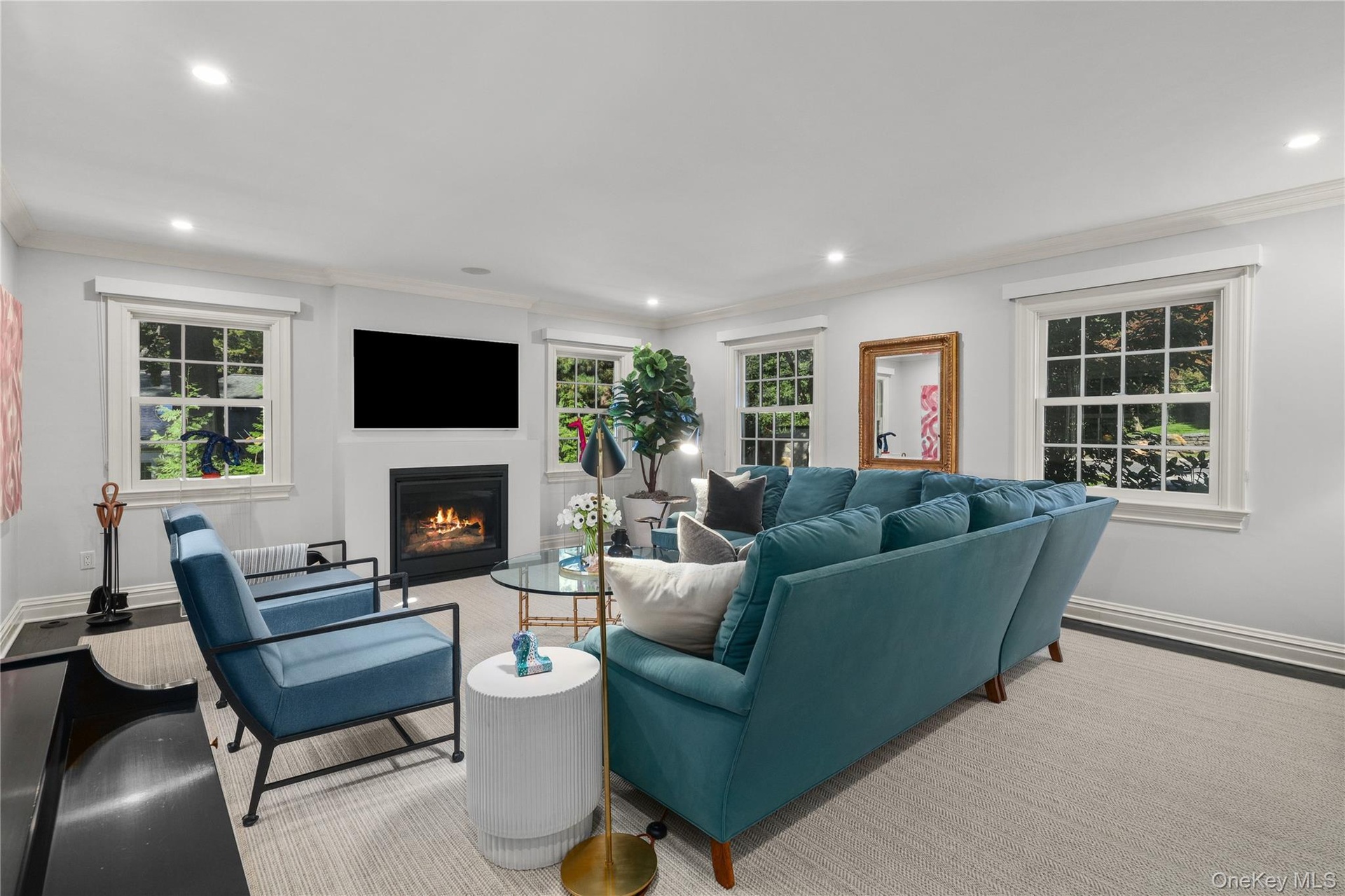 Fireplace with a black hearth and mantle, recessed lighting, and multiple windows with white trim