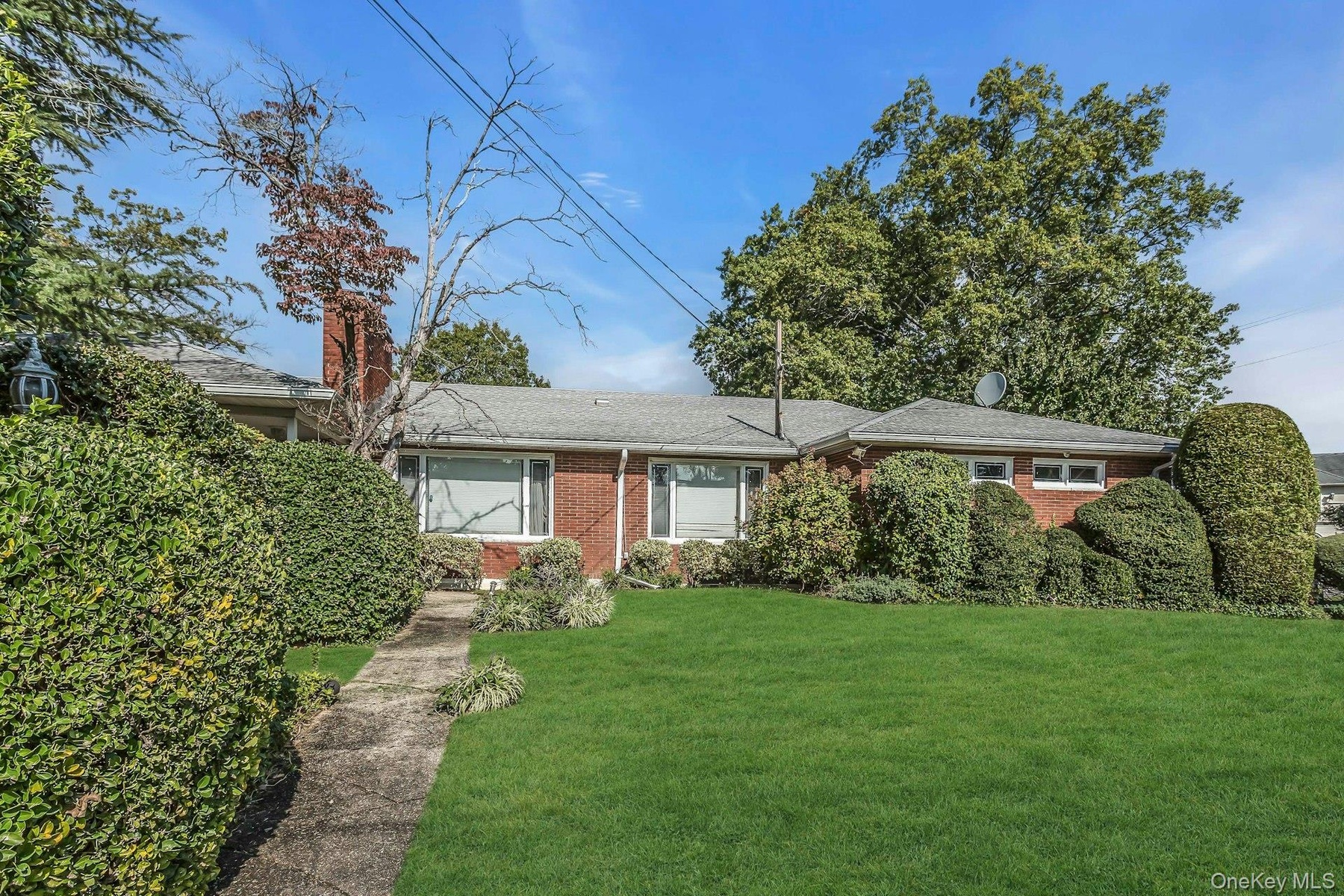 Single story home with brick siding, a front yard, a chimney, and a shingled roof