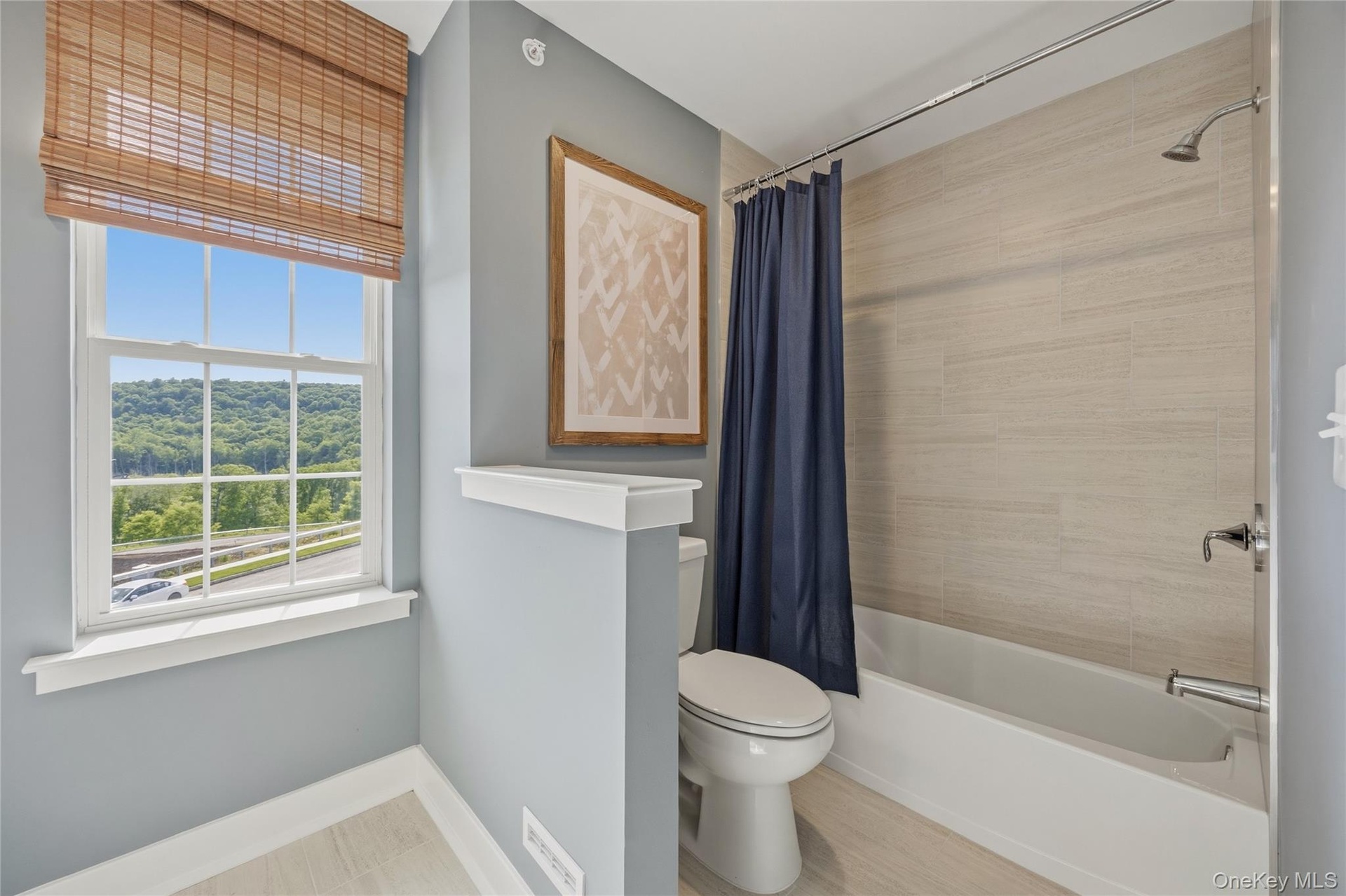 Bathroom featuring a window with a mountain backdrop, a full bathtub with a shower, textured wall tile, and light wood-finish flooring