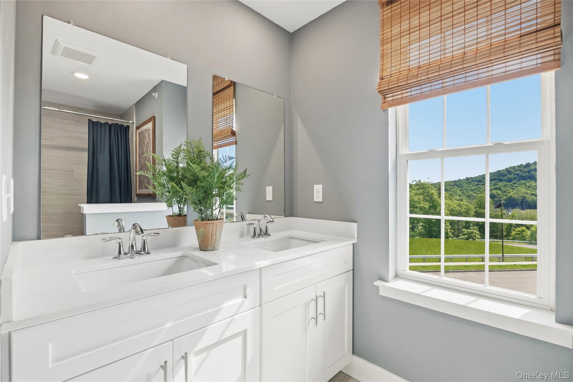 Bright bathroom featuring a double vanity with white cabinetry and light countertops.