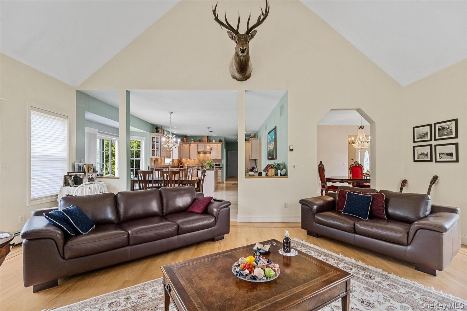 Living room with suspended lighting, light wood-type flooring, lofted ceiling, and arched walkways