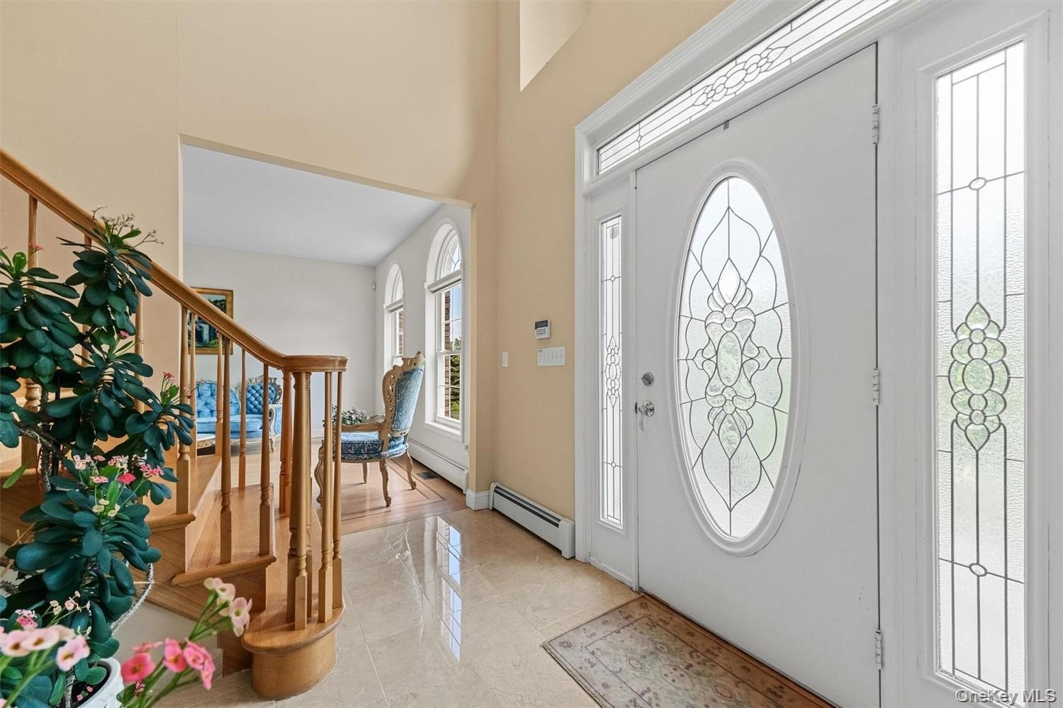 Foyer featuring a baseboard heating unit, a high ceiling, and light tile patterned floors