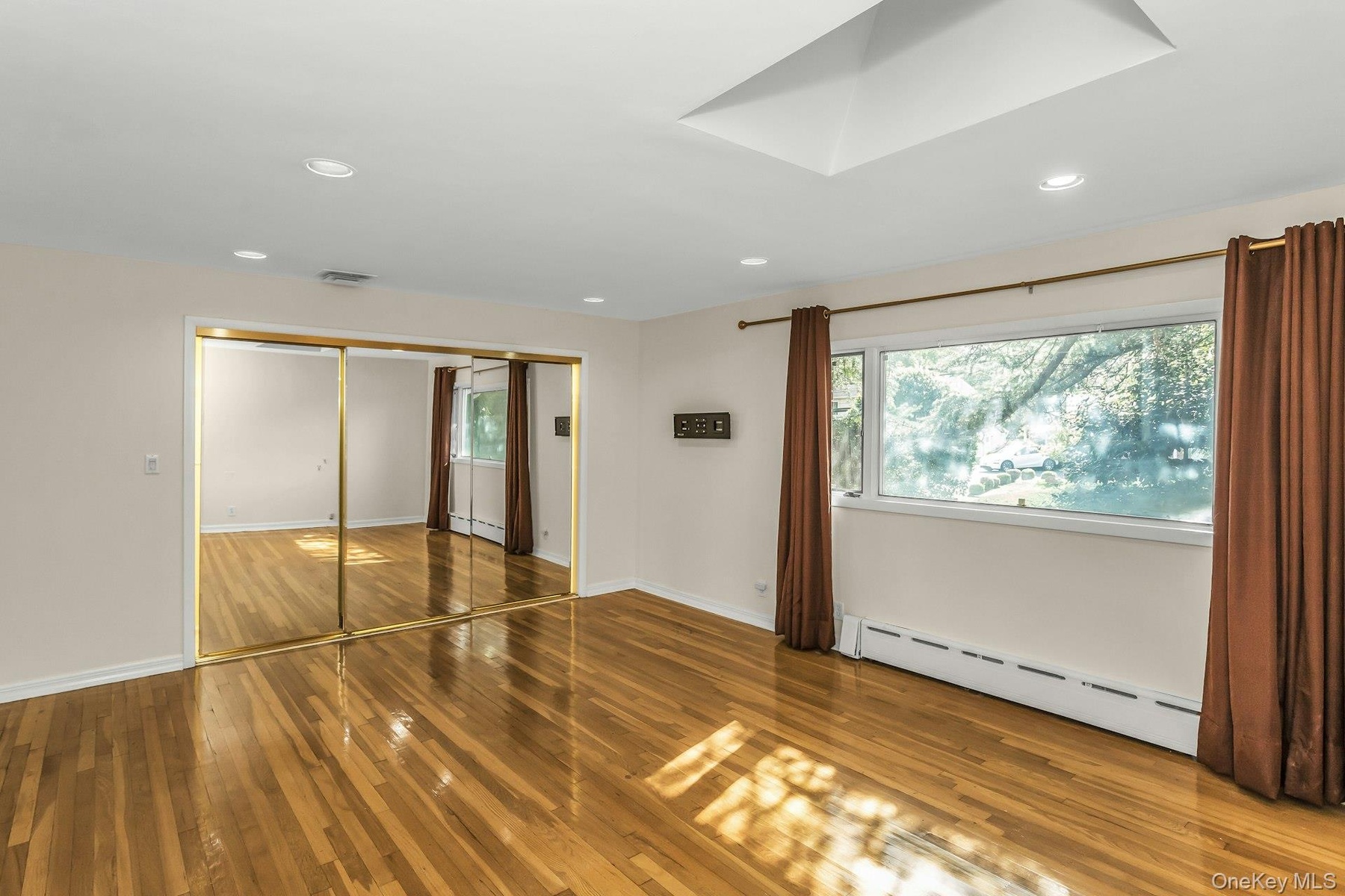 Unfurnished bedroom with a baseboard radiator, wood-type flooring, a closet, and recessed lighting