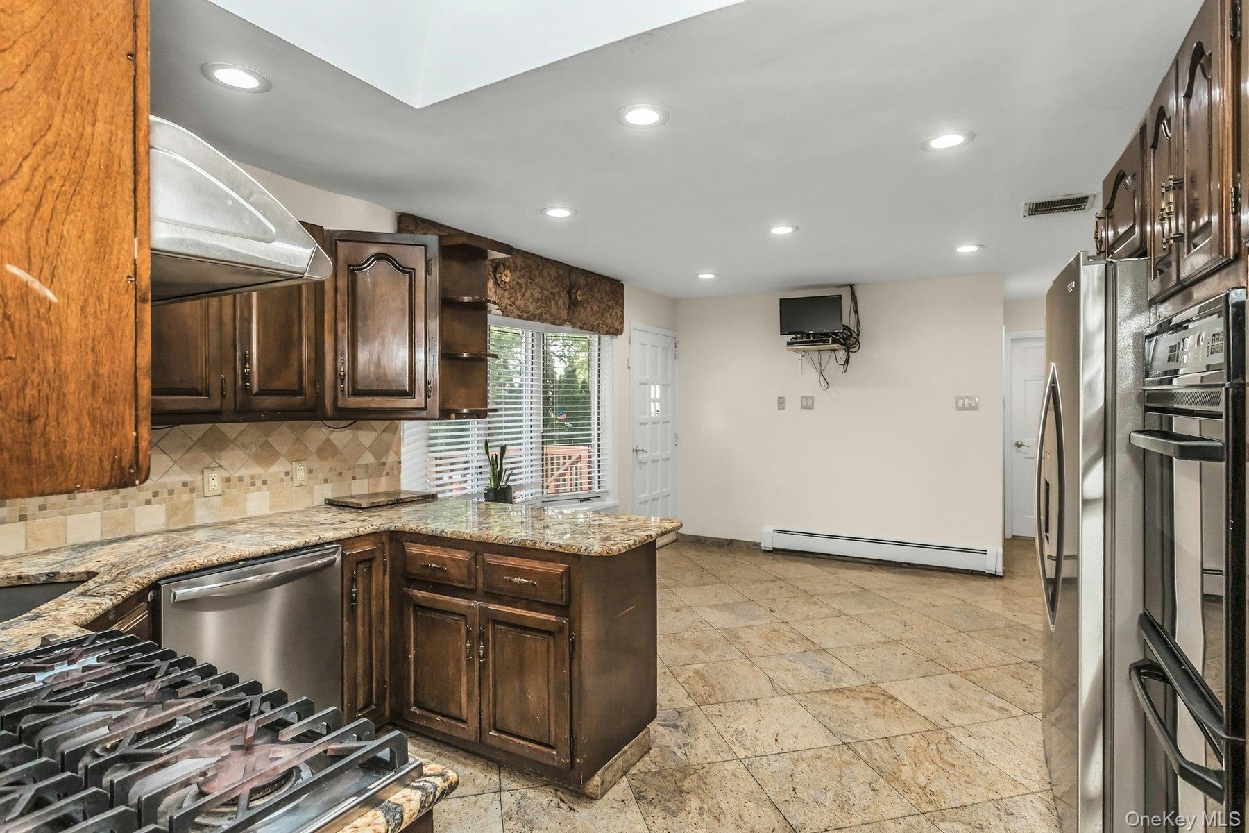 Kitchen featuring dark brown cabinetry, open shelves, light stone counters, backsplash, and recessed lighting