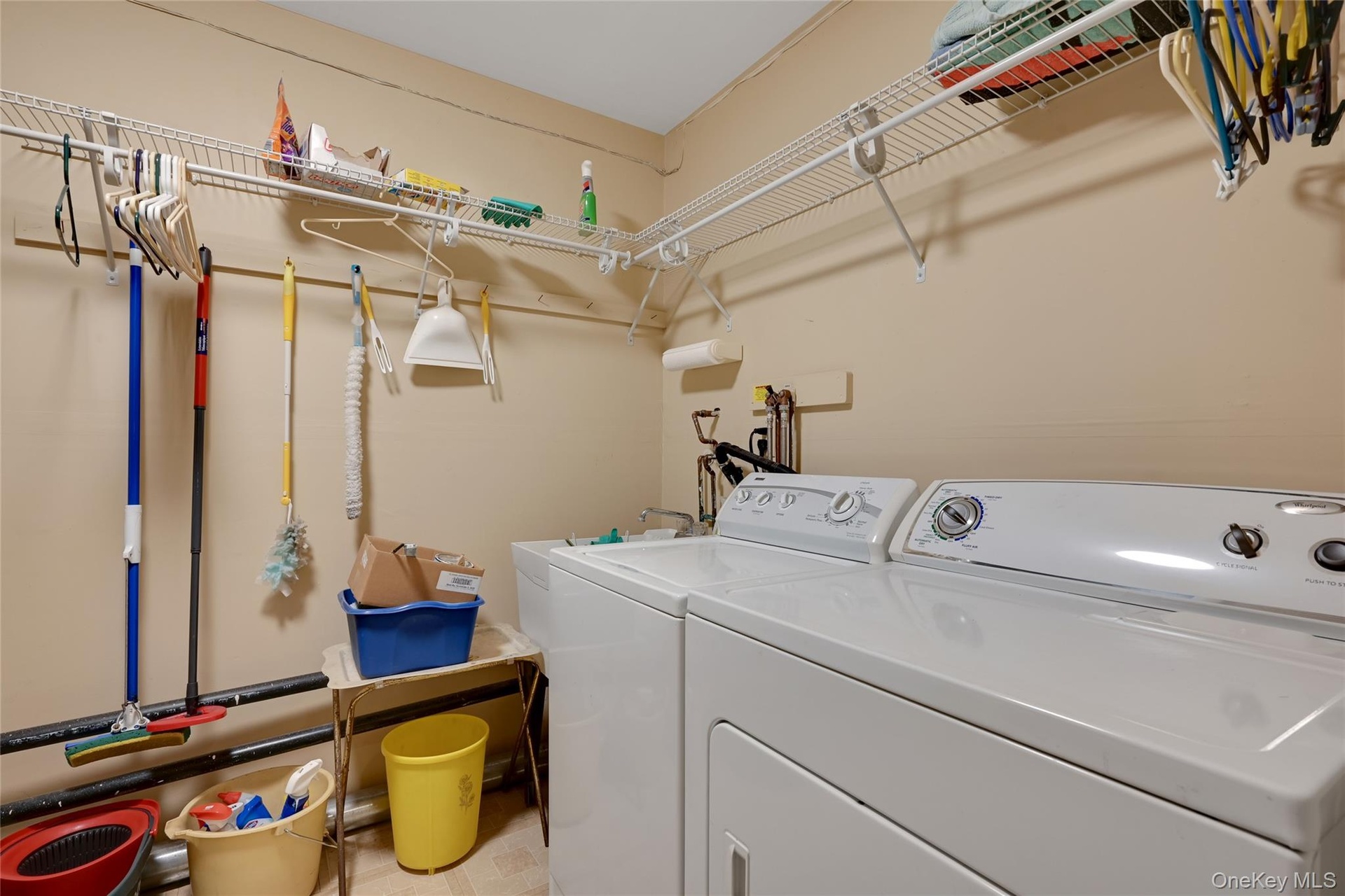 Dedicated laundry area featuring white washer and dryer, extensive wire shelving, and neutral wall paint