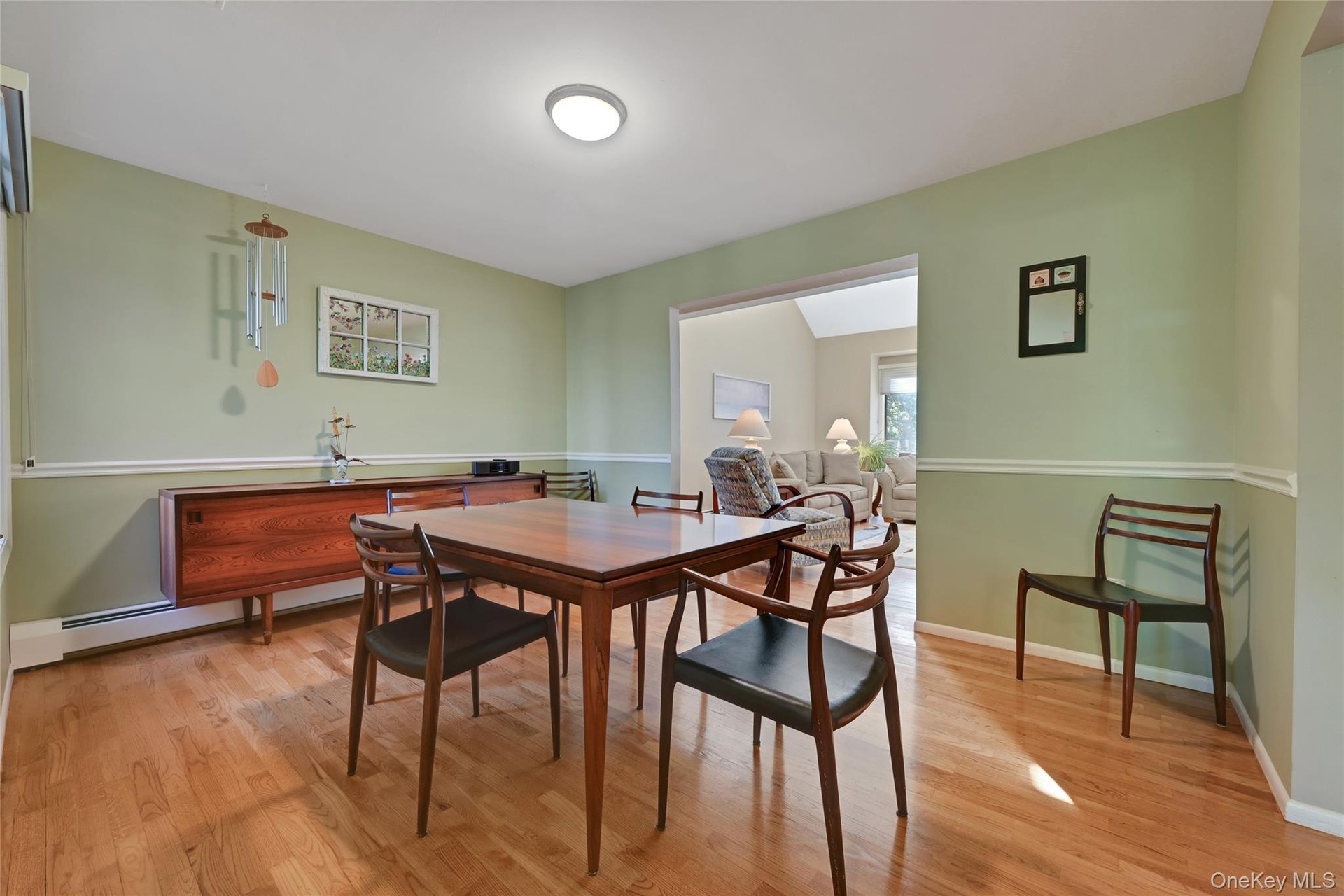 Hardwood flooring, chair rail molding, ceiling light fixture, and an open entryway to an additional room