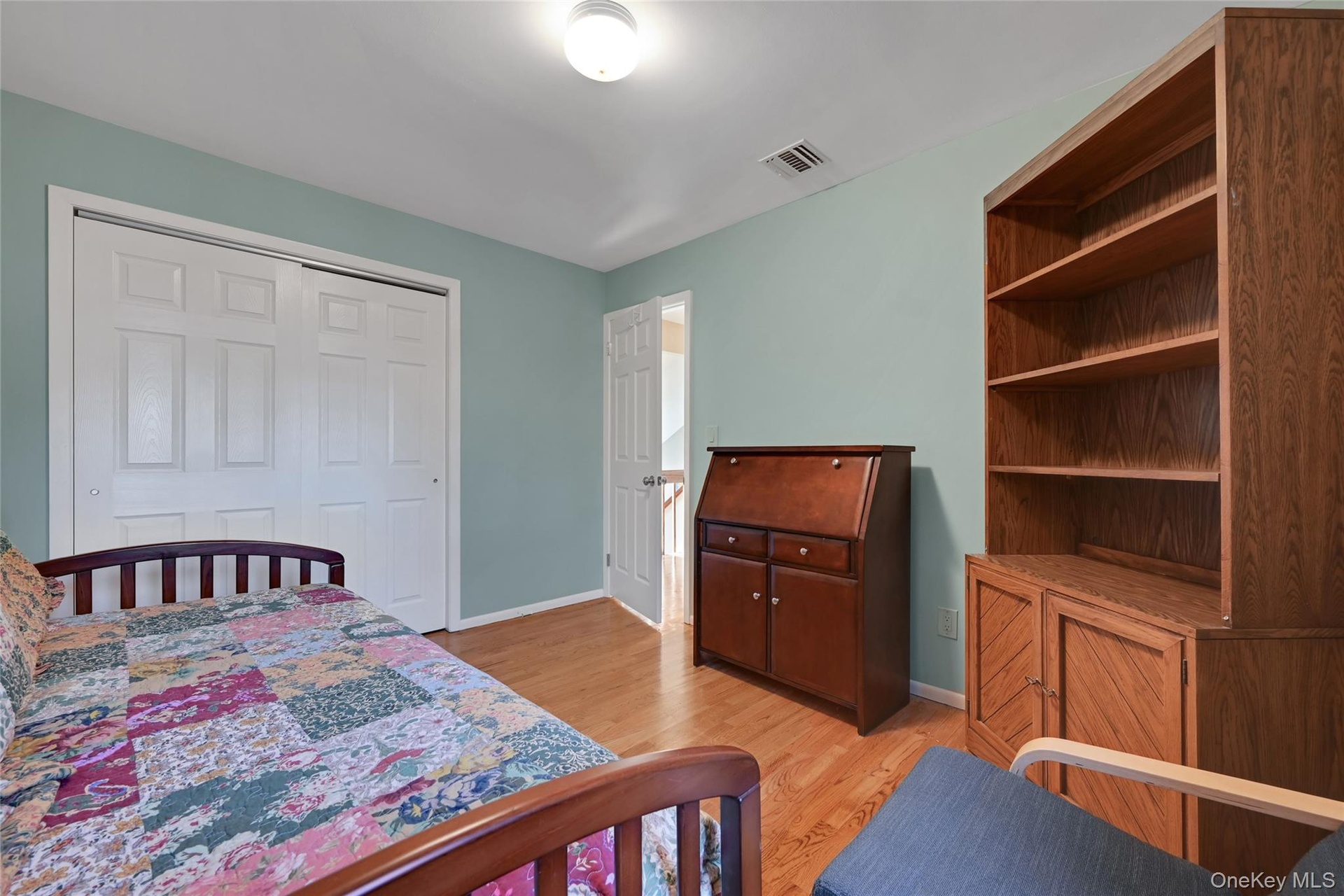 Recessed lighting, wood-finish flooring, and white paneled doors in second bedroom with double closet