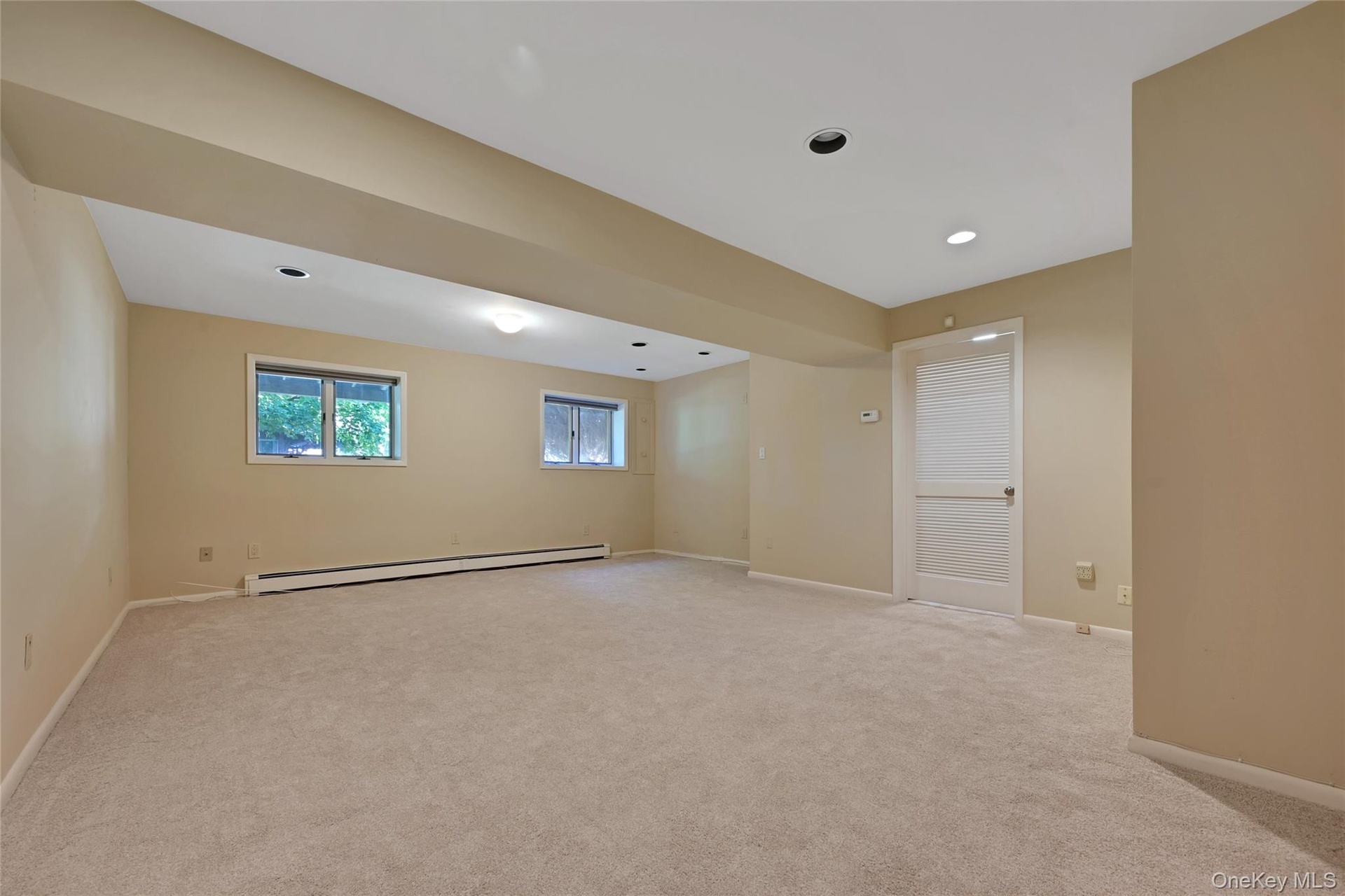 Spacious room featuring neutral new carpeting, recessed lighting, and two windows