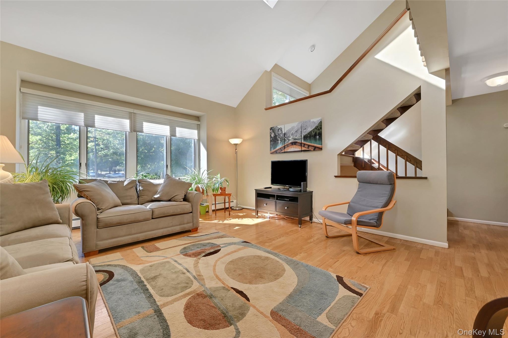 Vaulted ceiling, wood-finish flooring, large windows, wood staircase, and skylights