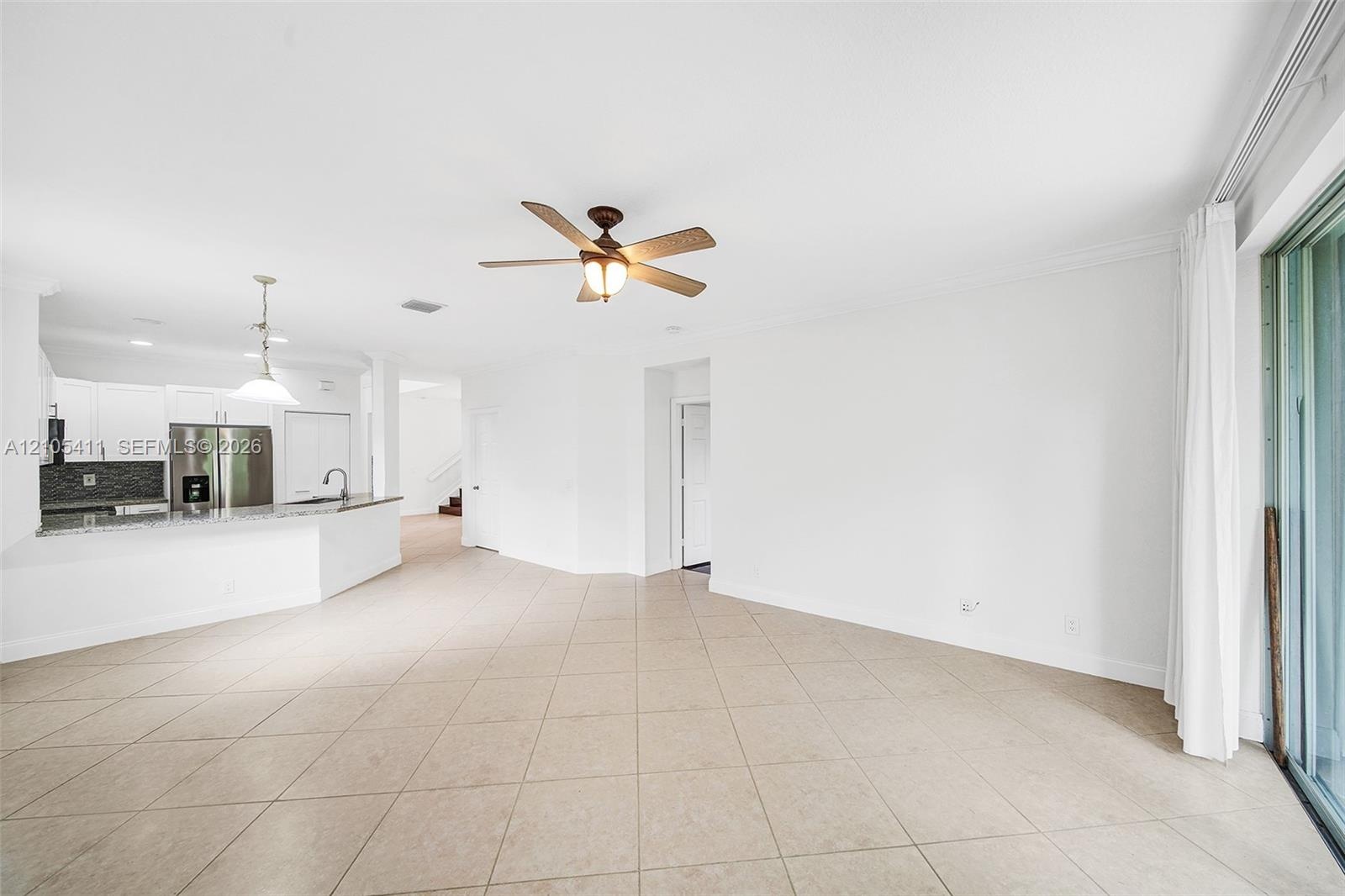 Open-concept living area with tile flooring, a ceiling fan, and sliding glass doors