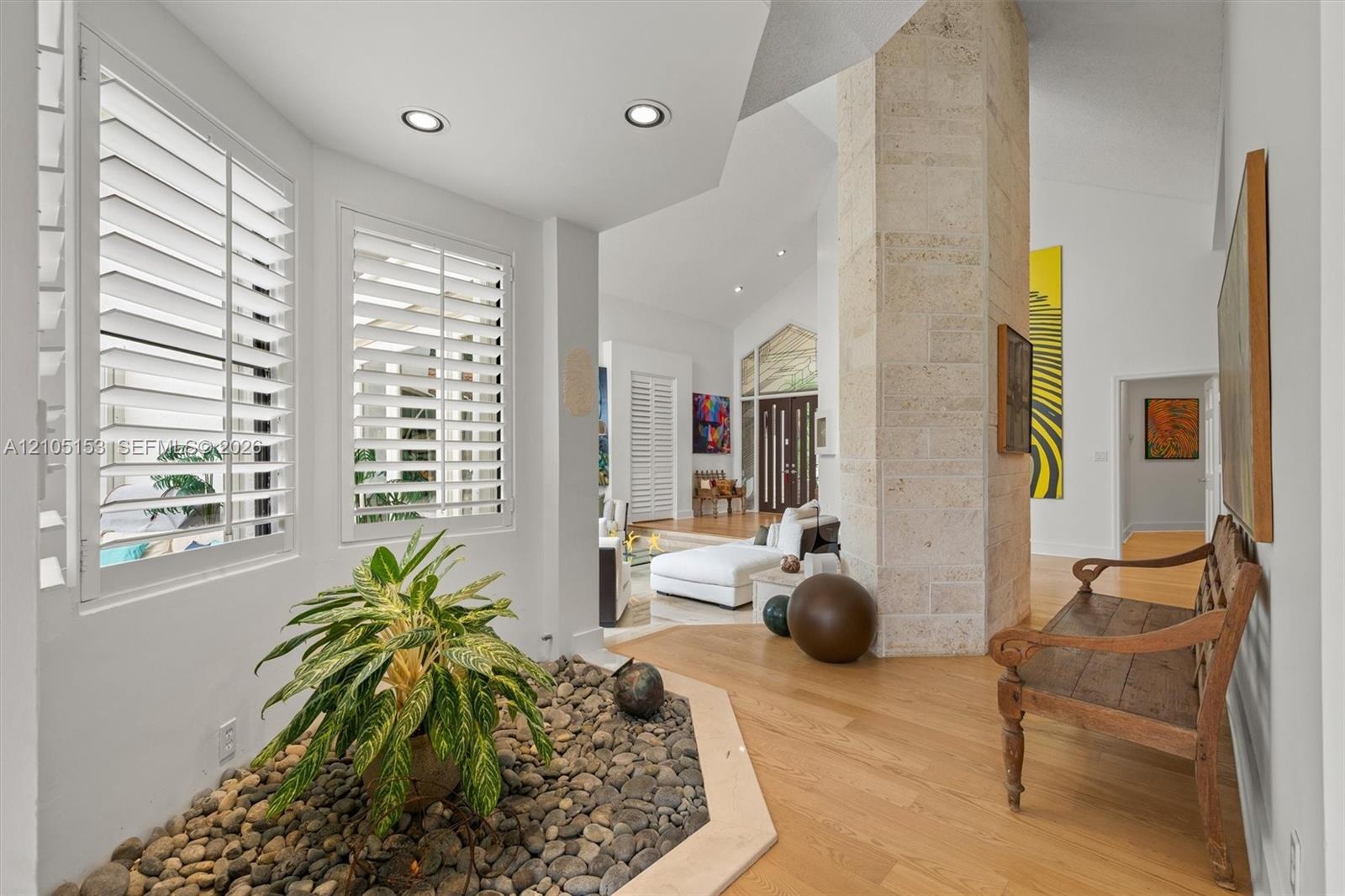 Vaulted ceilings, plank wood-finish flooring, recessed lighting, and a stone-clad architectural column
