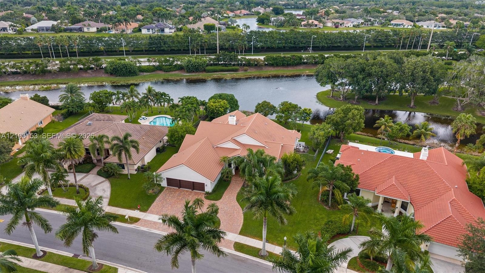 Tile roof property with a private pool, waterfront access, and mature palm trees