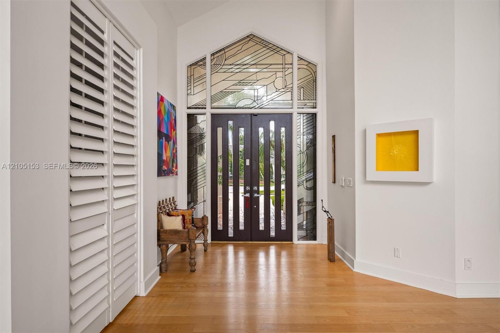Double entry doors with vertical glass panels, hardwood flooring, and a large architectural transom window