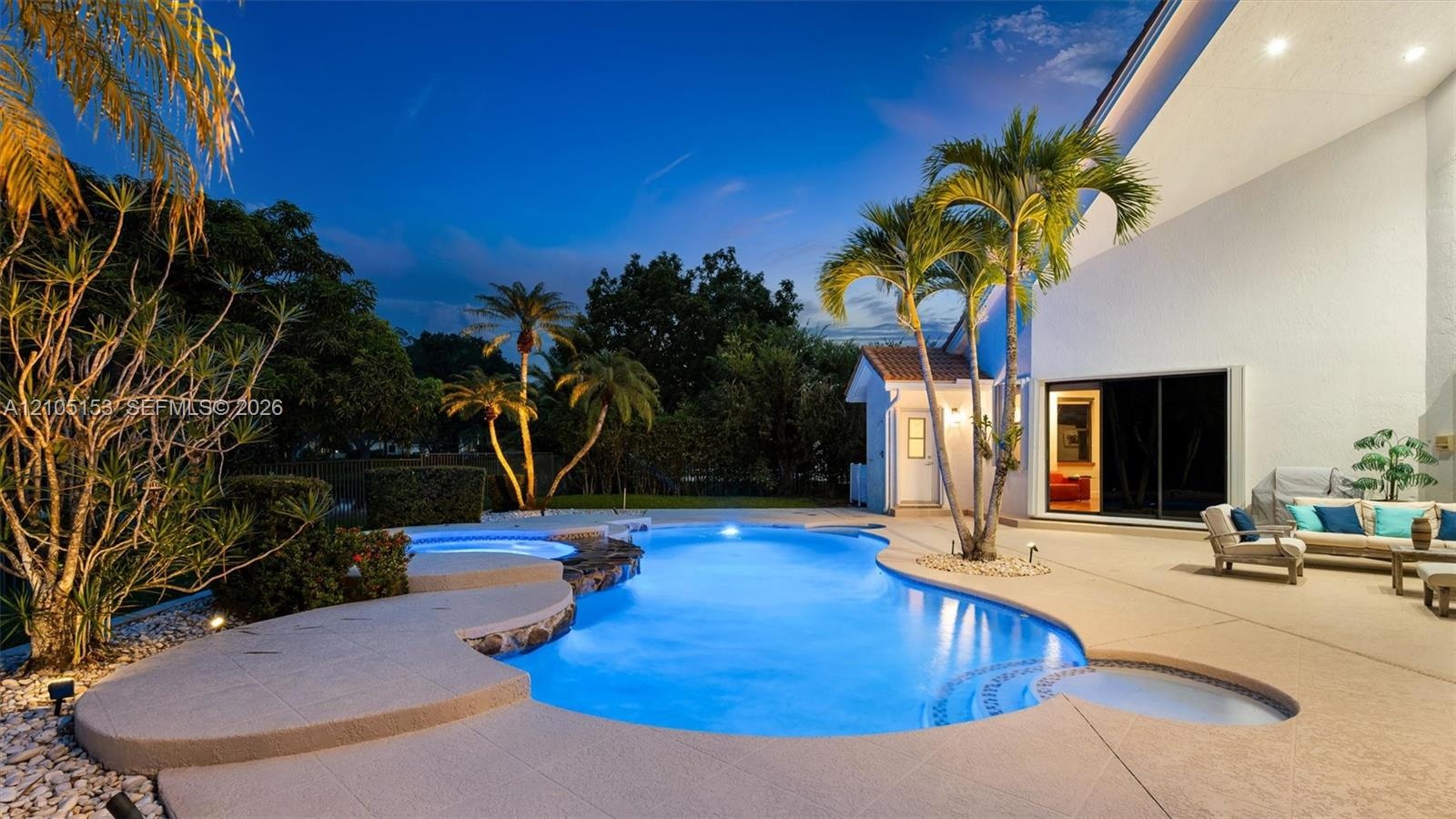 Curved swimming pool with integrated spa and stone waterfall feature