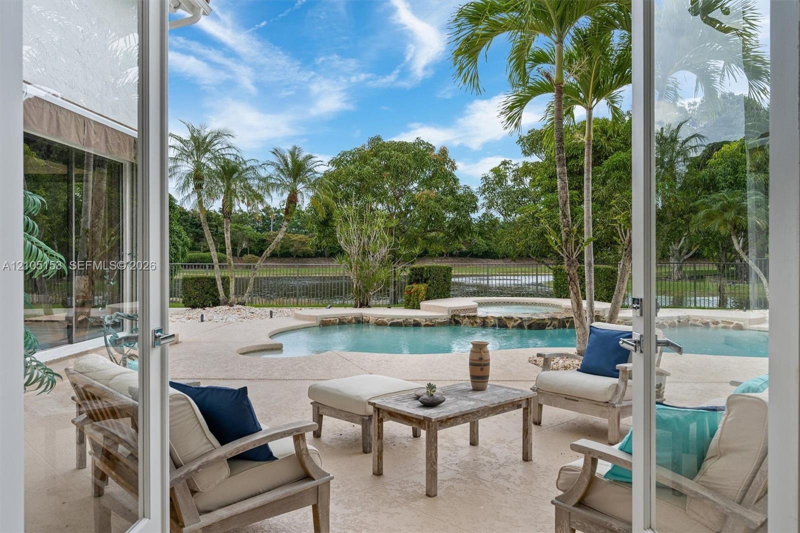 Outdoor patio area with a free-form pool, integrated spa, and mature palm trees