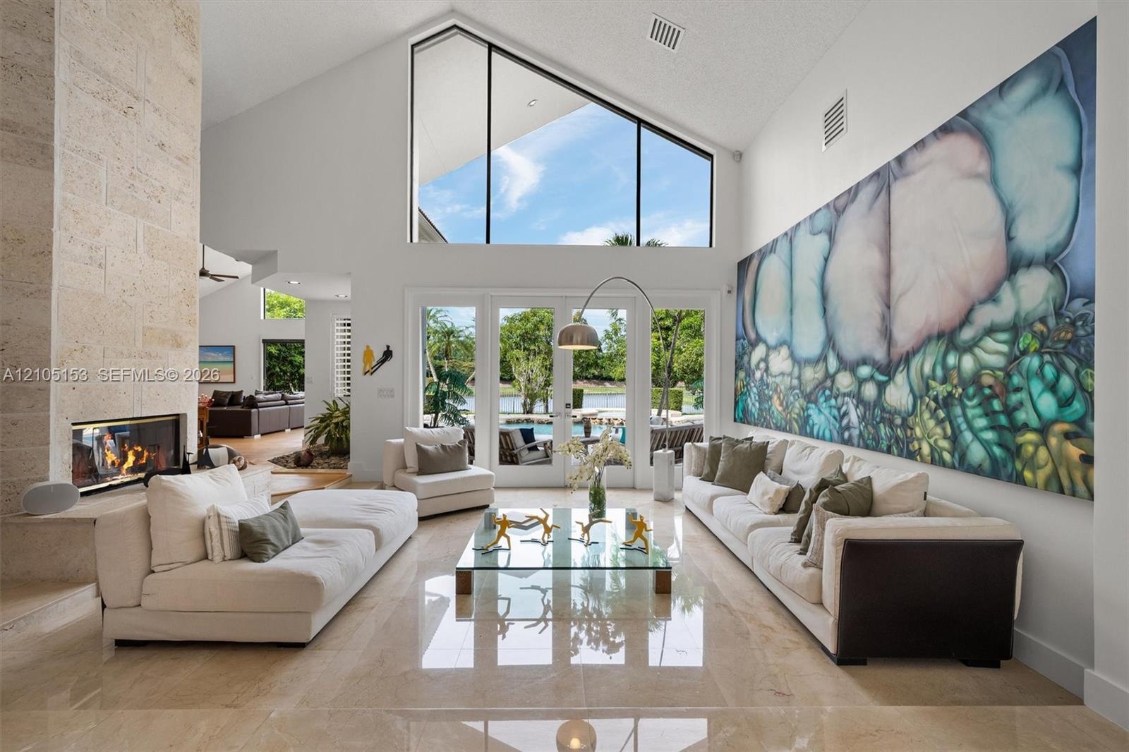 Vaulted ceilings with expansive transom windows, large glass patio doors, a built-in fireplace with stone surround, and polished floor tiles