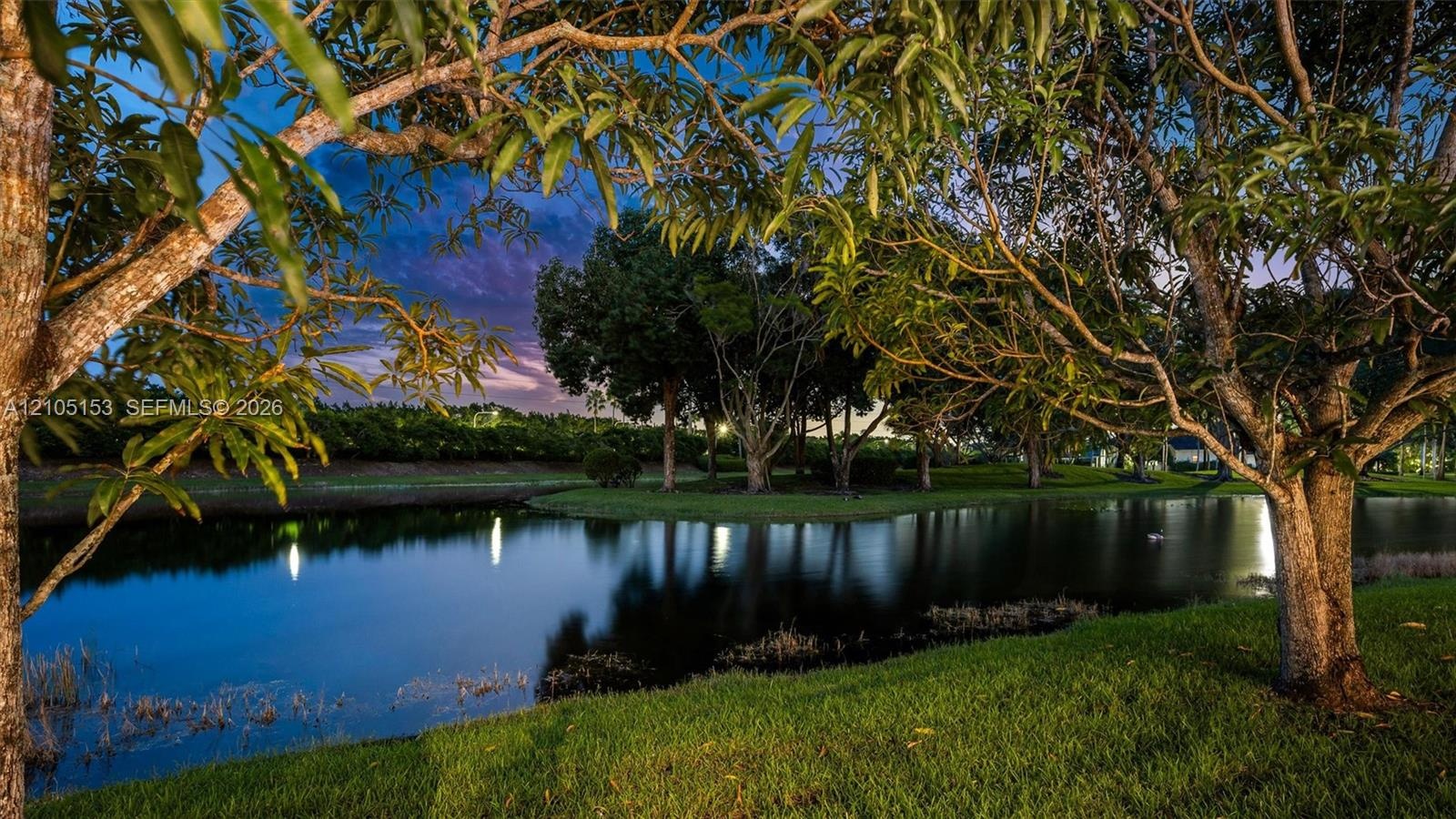 Lush landscaping with mature trees, verdant grass, and a tranquil pond