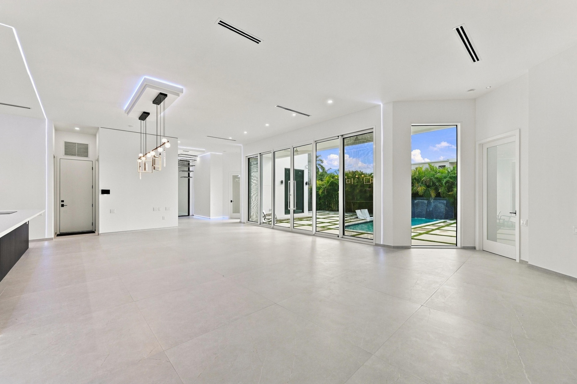 Expansive open-concept interior with polished concrete flooring, recessed ceiling lighting, and floor-to-ceiling glass sliding doors and windows frami