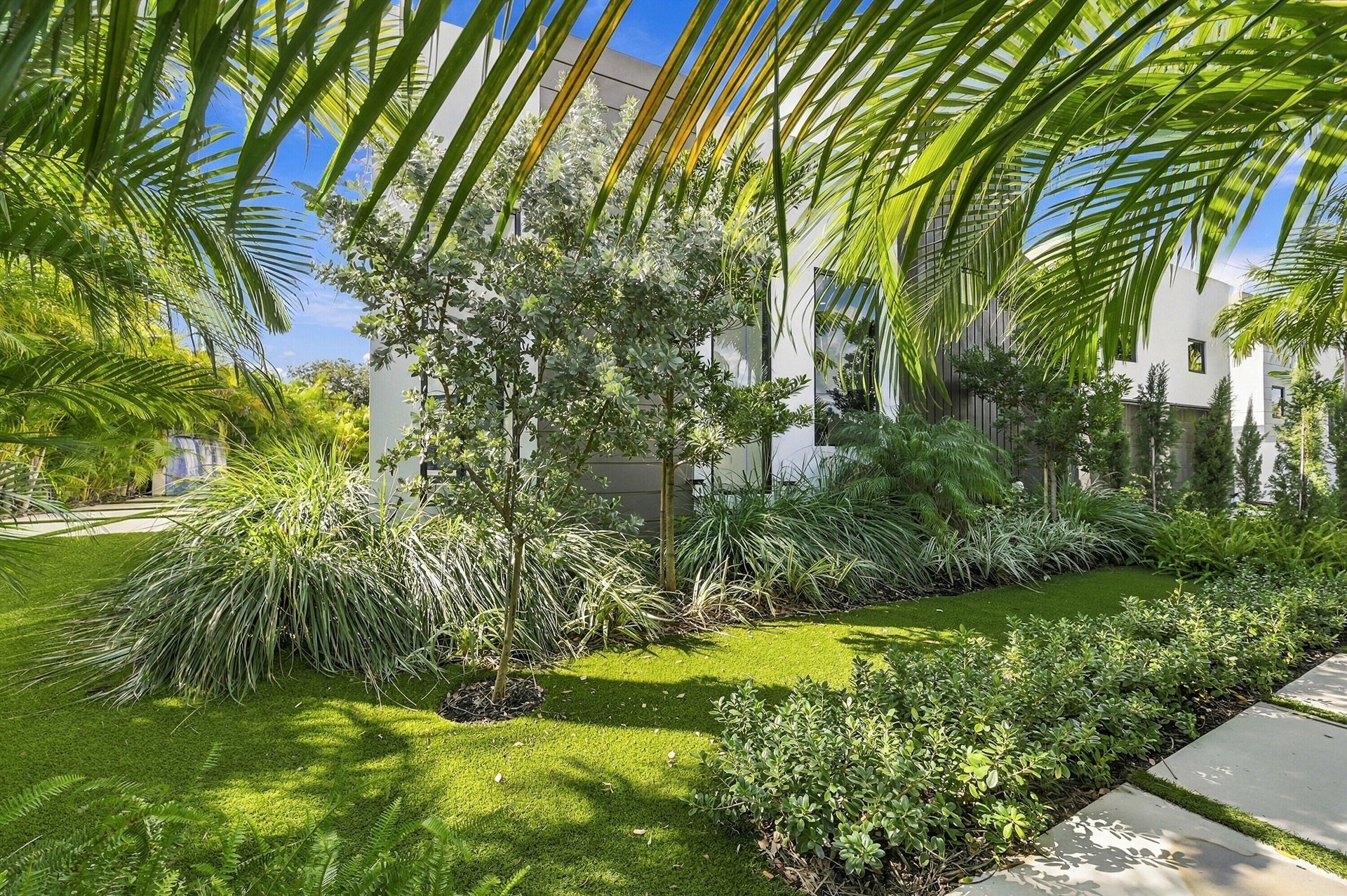 Lush tropical landscaping with mature palm trees, manicured lawn, and established shrub borders frames this serene outdoor setting