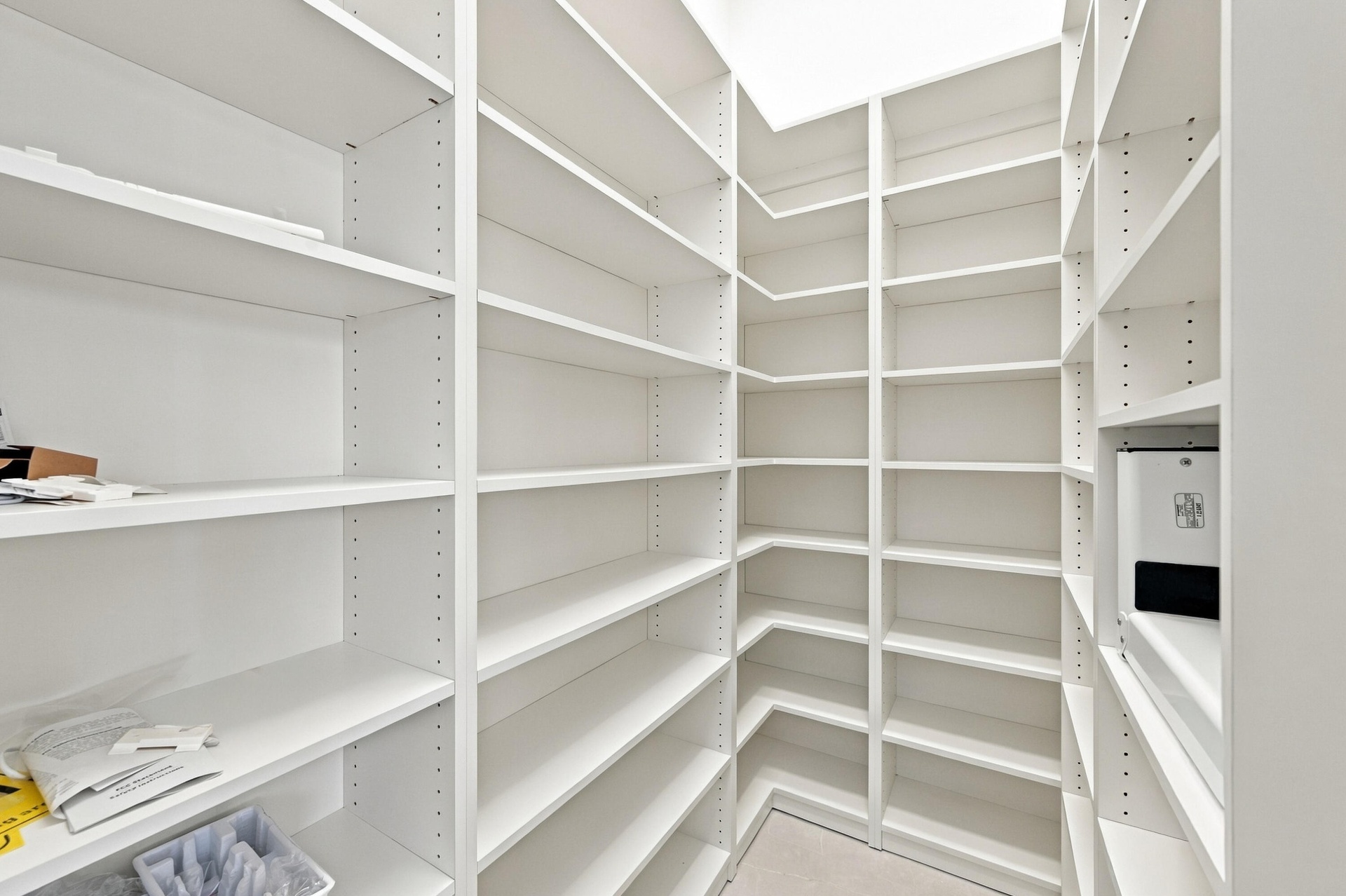 Spacious pantry featuring extensive built-in shelving with adjustable shelves throughout, white finish cabinetry, and bright overhead lighting