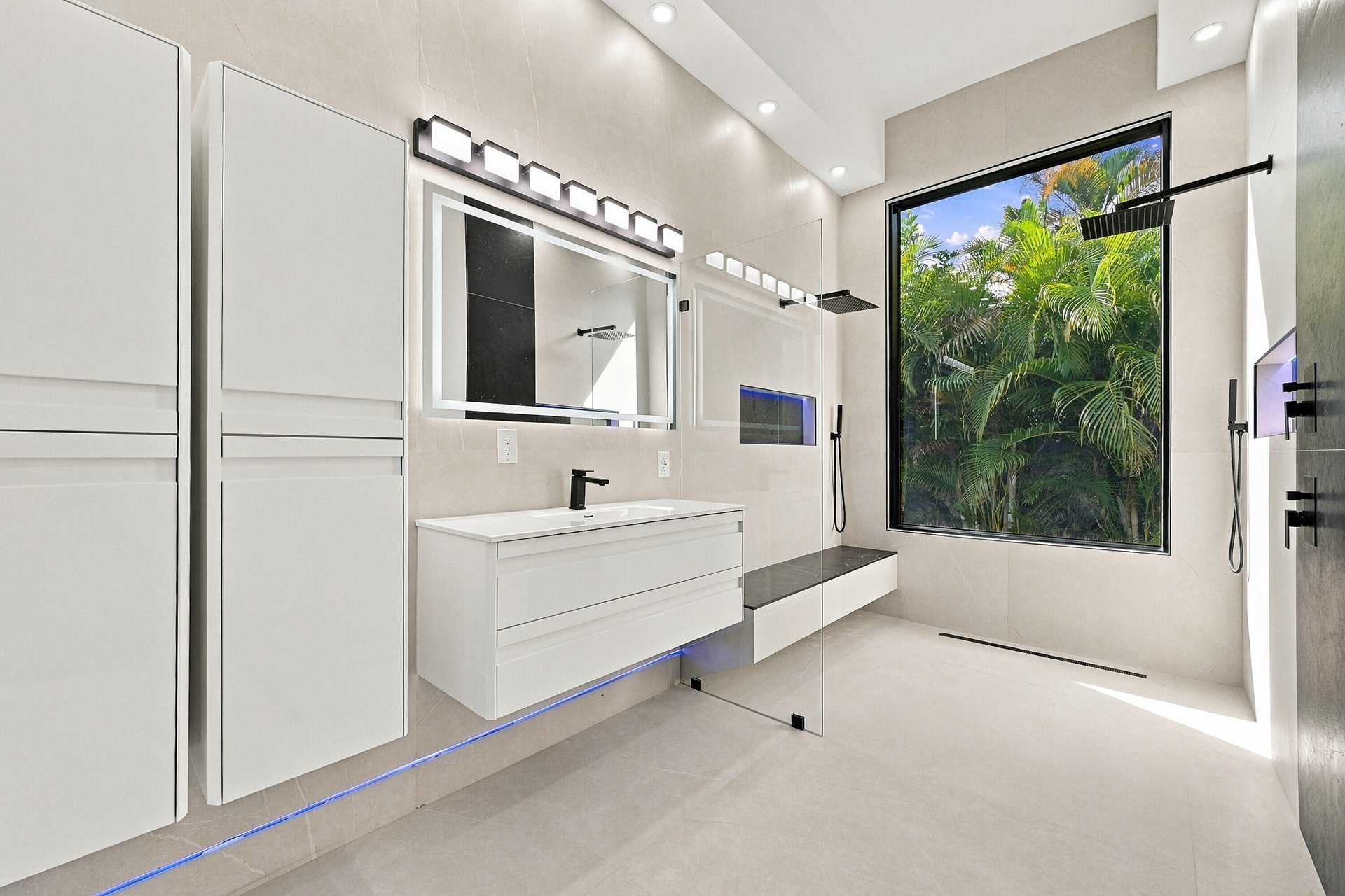 Spa-inspired primary bathroom featuring a floating white vanity with integrated sink, frameless glass shower enclosure, linear ceiling lighting, and l