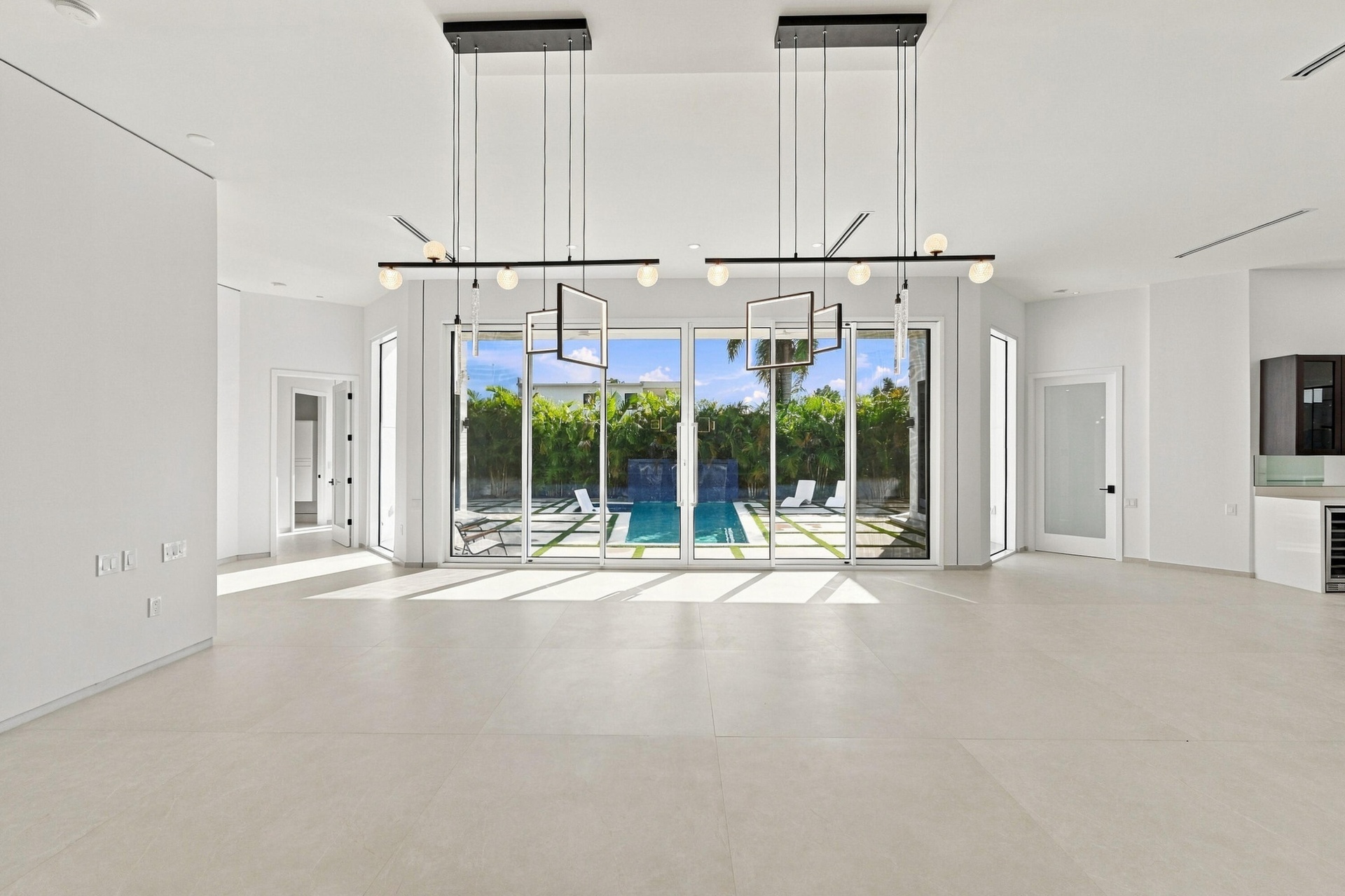 Expansive open-concept room with light-toned flooring and multiple floor-to-ceiling glass sliding doors