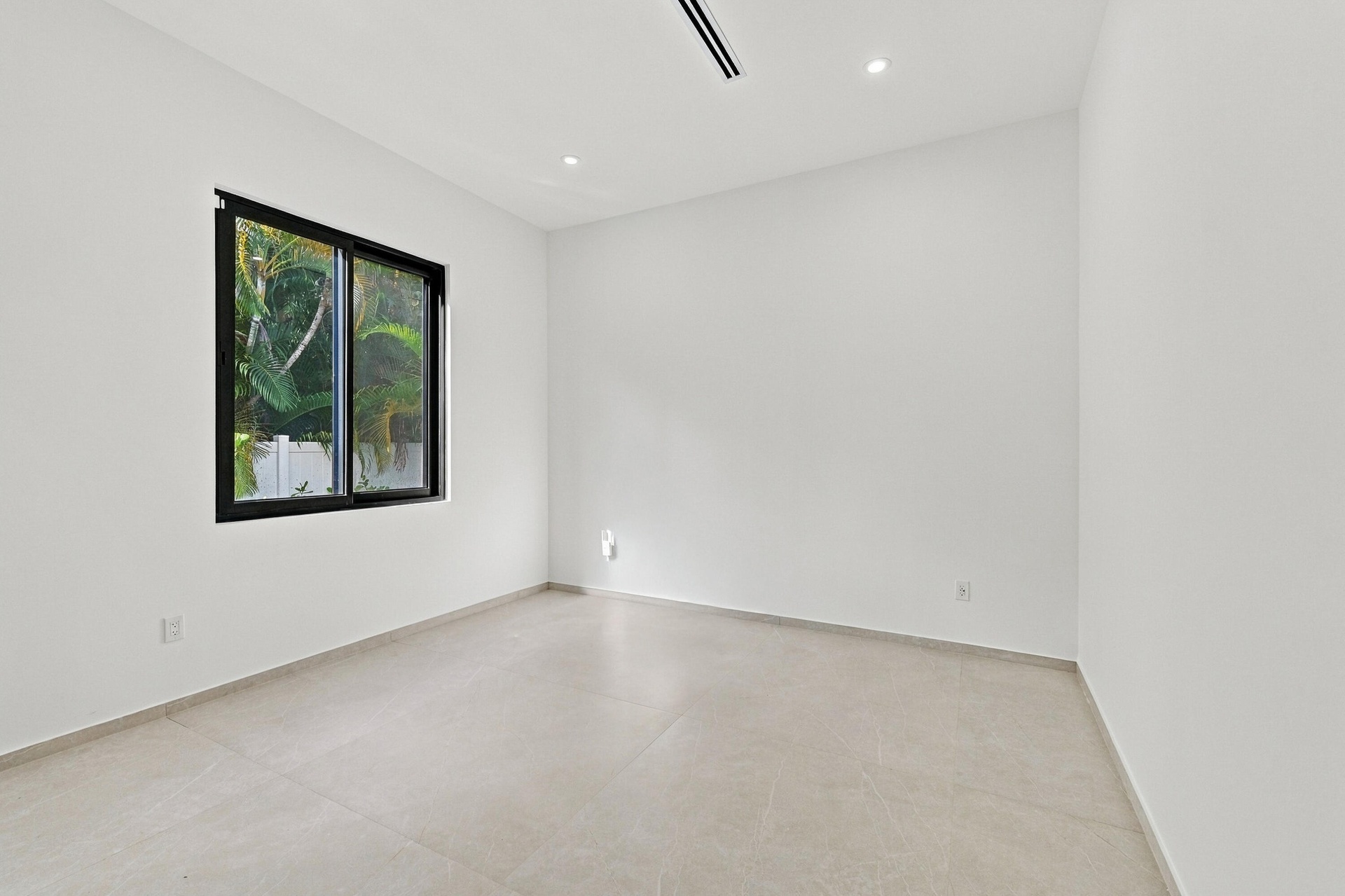 Bright, minimalist bedroom showcasing polished concrete flooring, clean white walls, and abundant natural light from a black-framed window