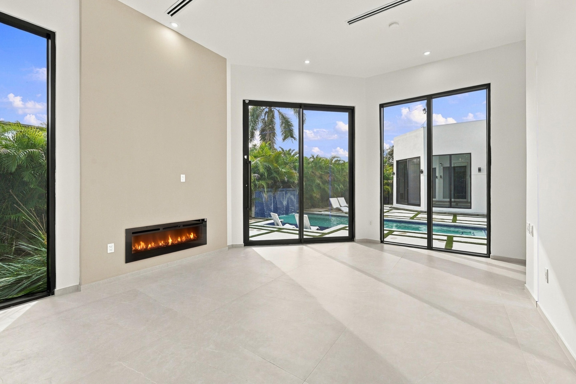 Bright, open-concept living space featuring polished concrete flooring, recessed ceiling lighting, and a linear electric fireplace with black surround