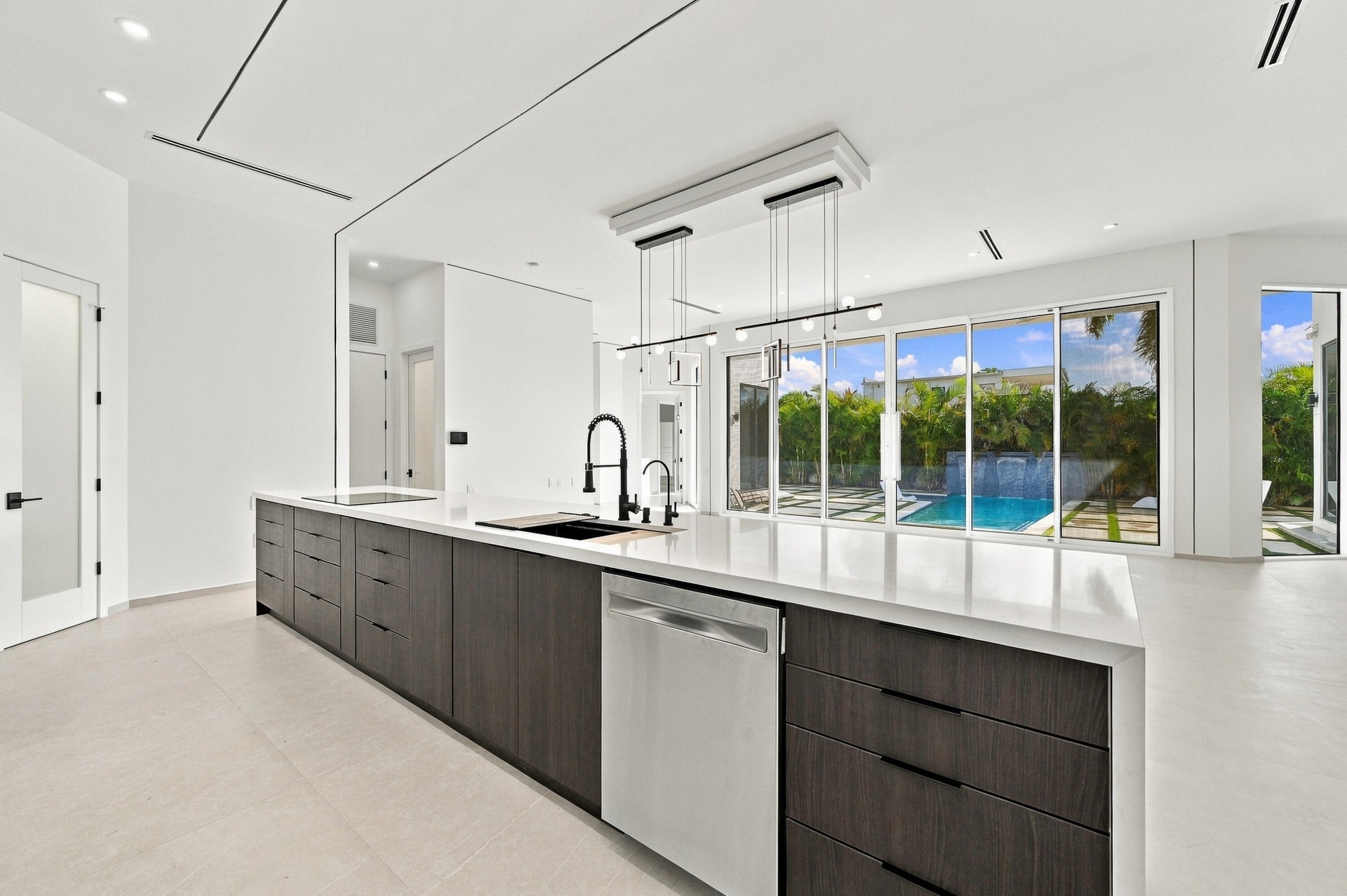 Chef's kitchen featuring a substantial island with wood-finish cabinetry, white quartz countertops, integrated dishwasher, and matte black faucet with