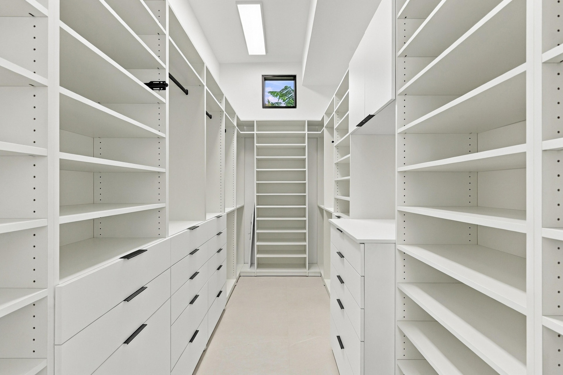 Custom closet system featuring extensive shelving, built-in drawers with modern hardware, integrated hanging rods, and a task ladder