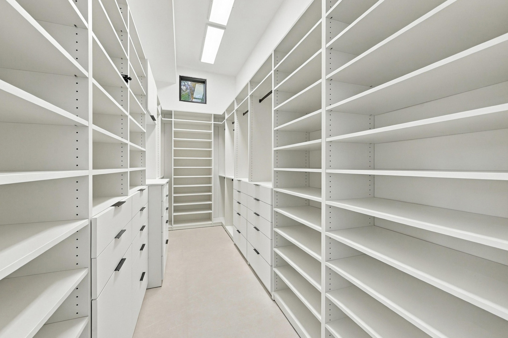 Custom closet system featuring extensive shelving, built-in drawers with modern pulls, and integrated lighting