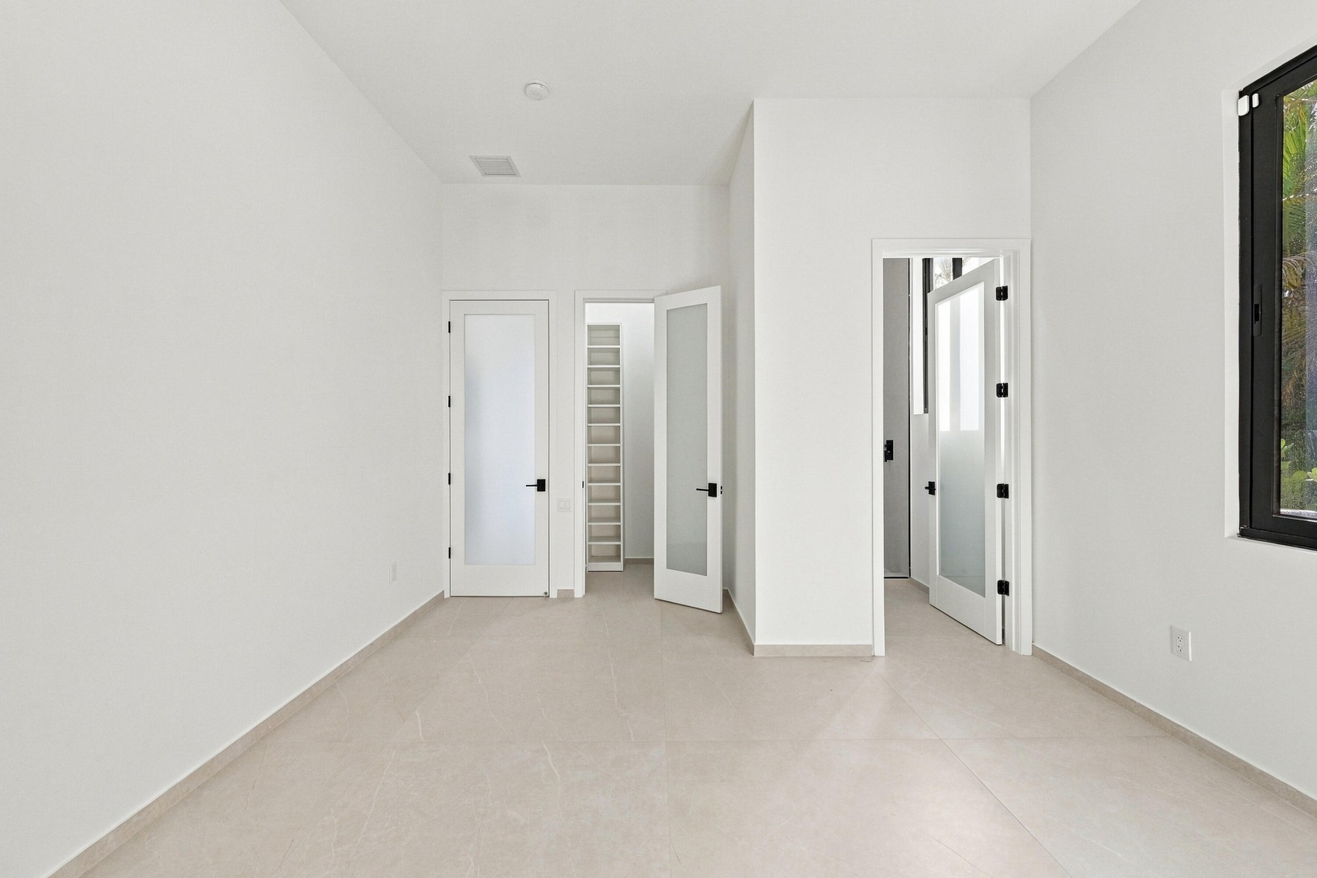 Bright, open interior featuring multiple white panel doors with black hardware, neutral flooring throughout, and clean white walls with recessed ceili