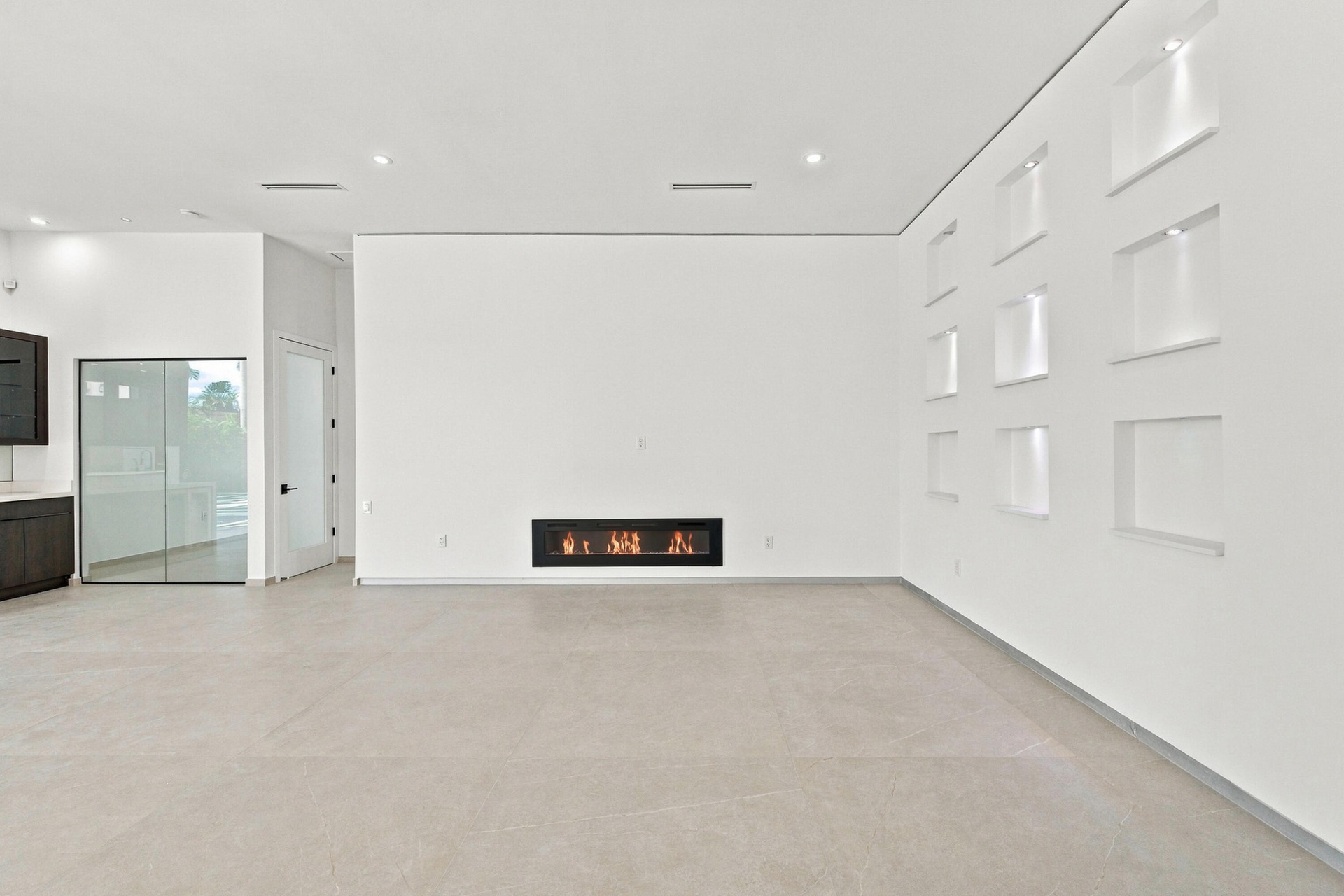 Built-in linear fireplace, recessed wall niches with accent lighting, dark wood-finish cabinetry, light-toned flooring, and recessed ceiling lighting