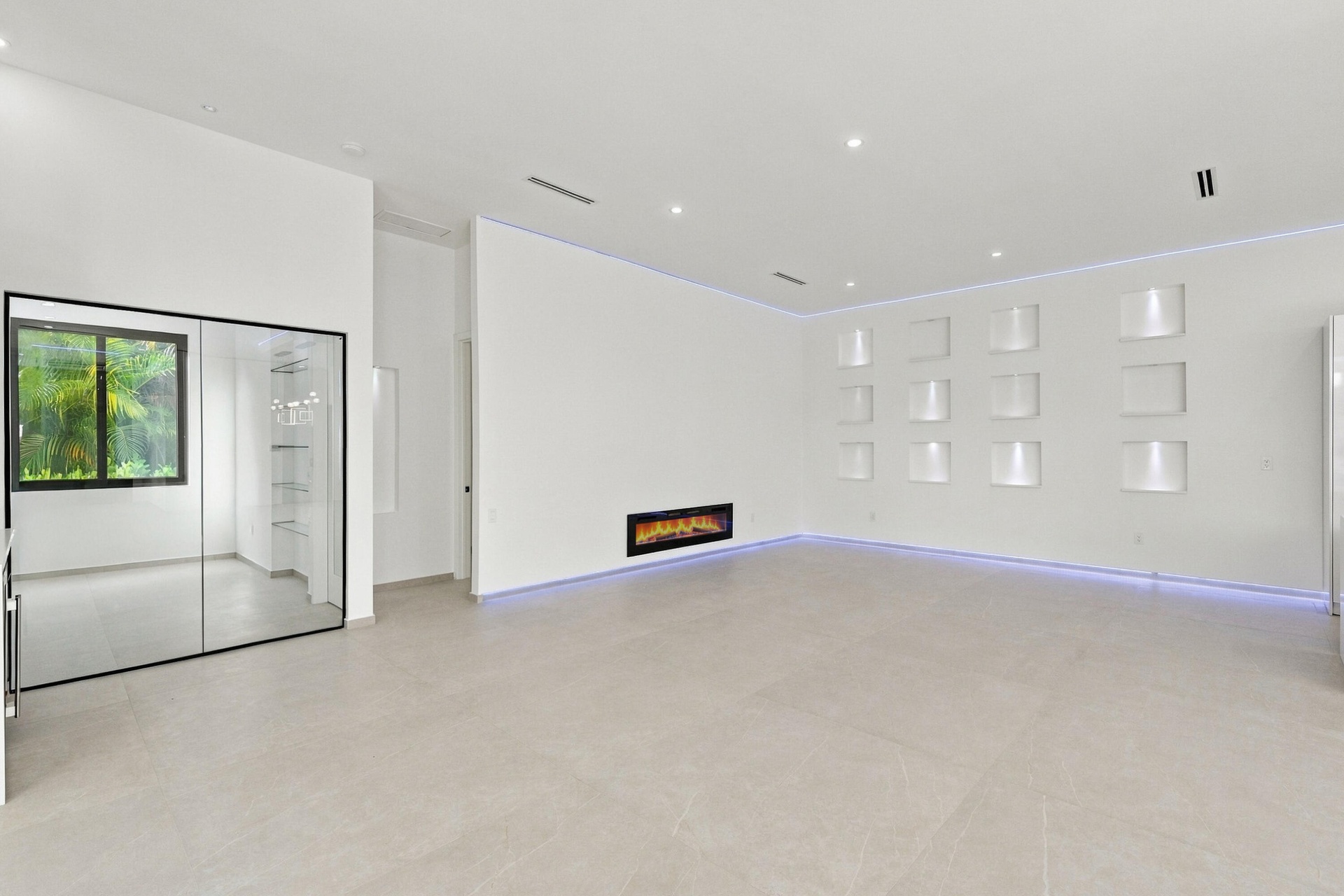 Spacious open-concept room featuring polished concrete flooring, recessed ceiling lighting, and a linear electric fireplace