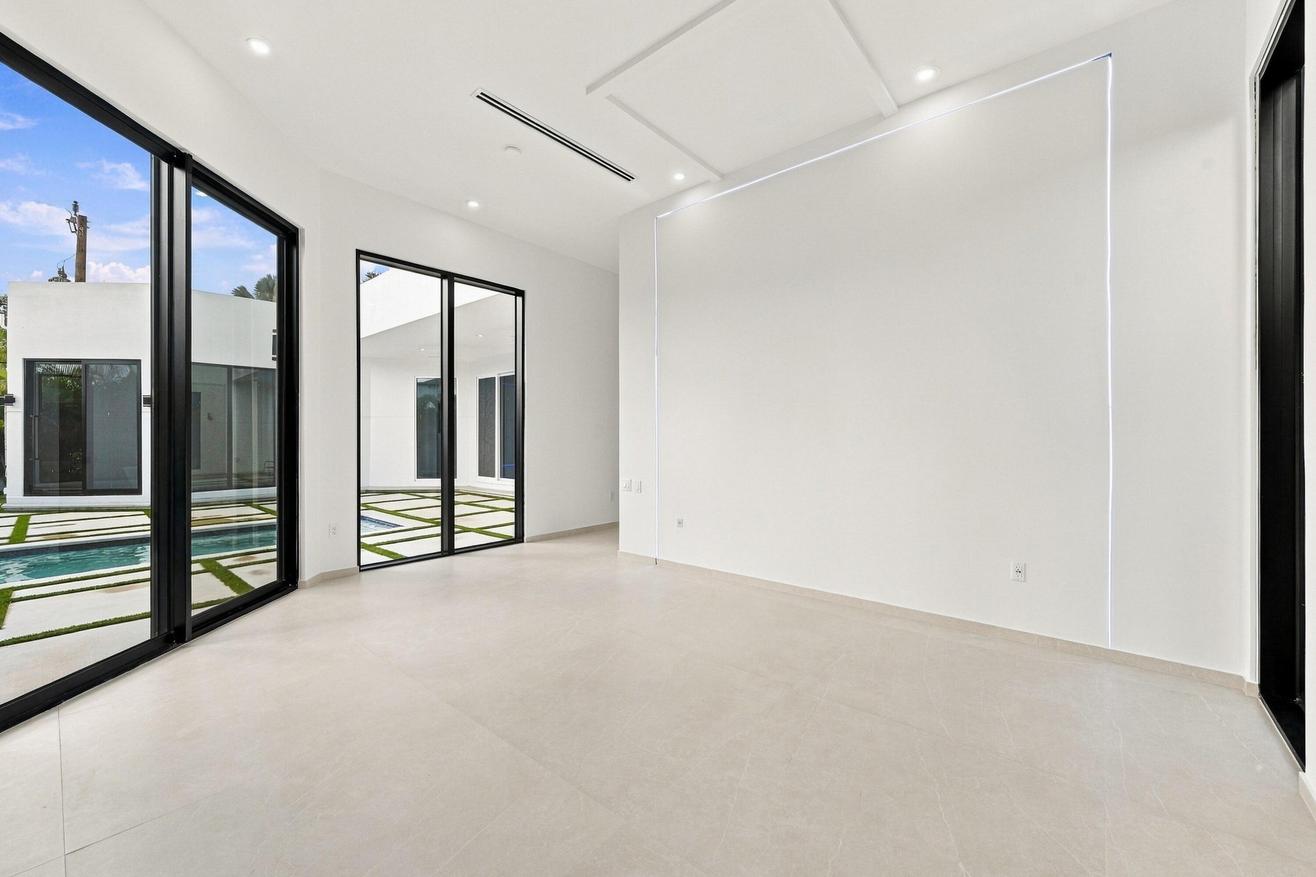 Expansive room with large format tile flooring, recessed lighting, and a tray ceiling