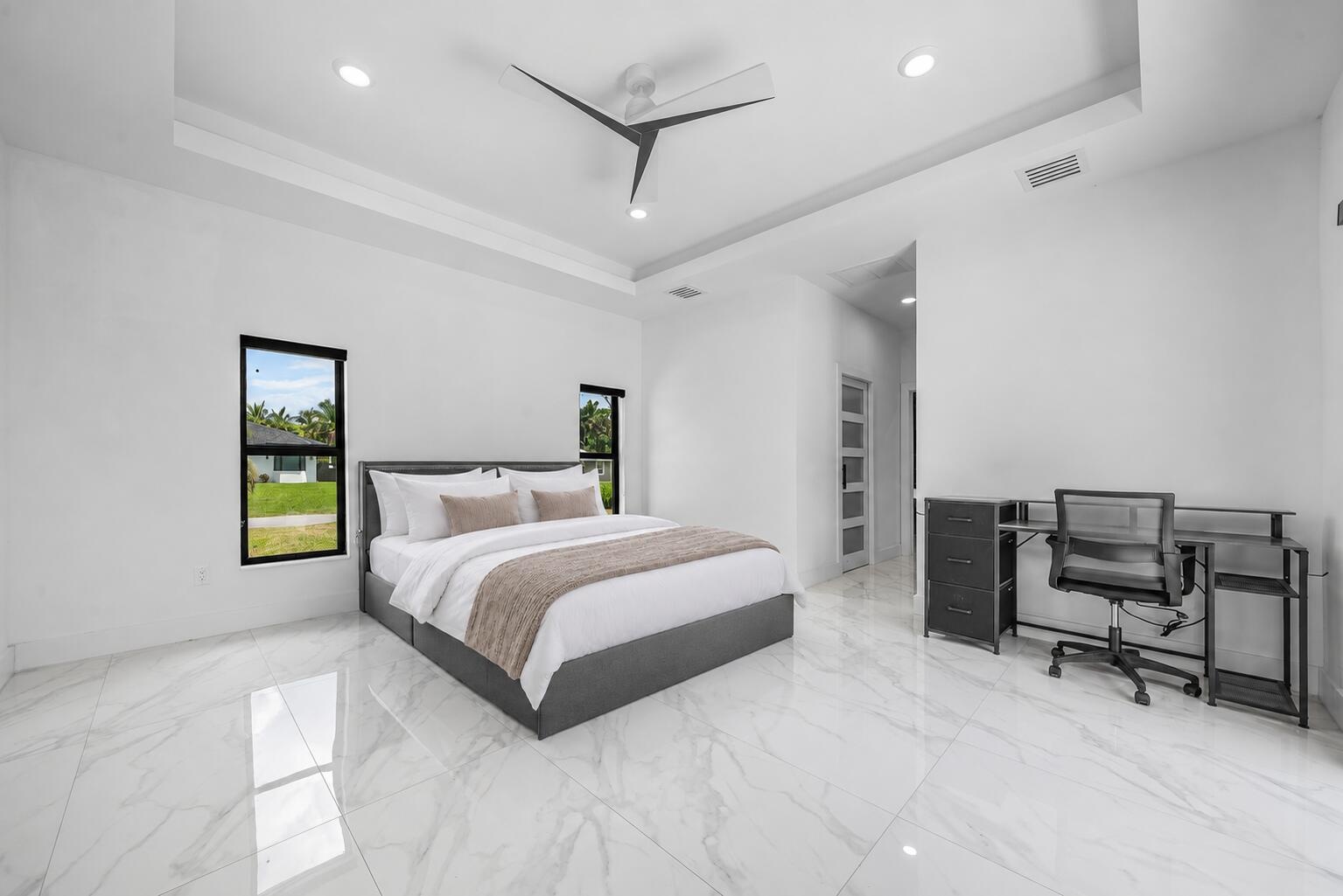 Spacious room featuring white tile flooring, tray ceiling, recessed lighting, and two windows