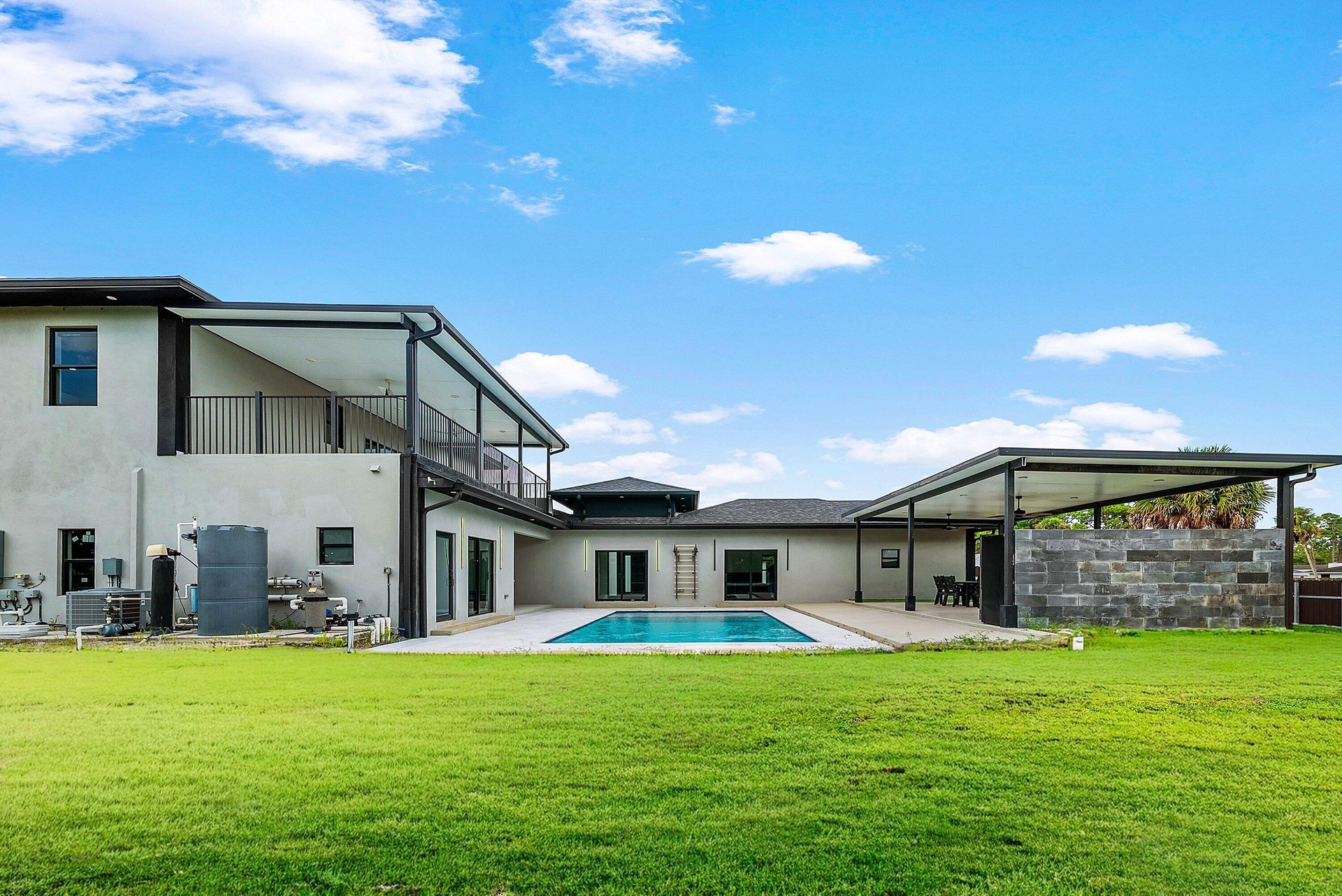 Expansive outdoor area featuring a swimming pool, covered patio, and large grassy lawn
