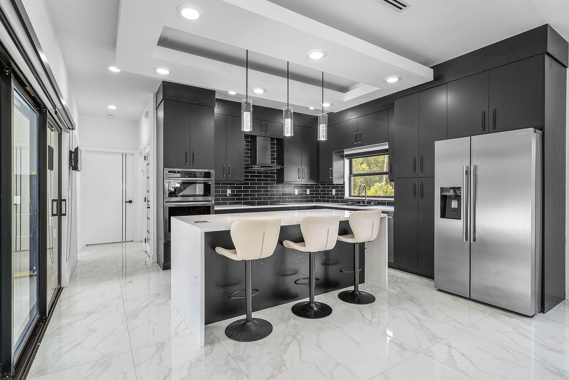 Contemporary kitchen featuring dark wood cabinetry, a waterfall island, and stainless steel appliances