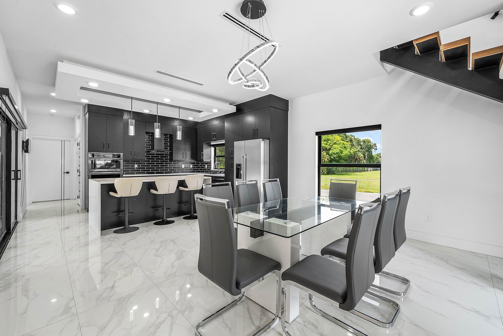 Modern kitchen featuring dark cabinetry, stainless steel appliances, a breakfast bar, and white tile flooring