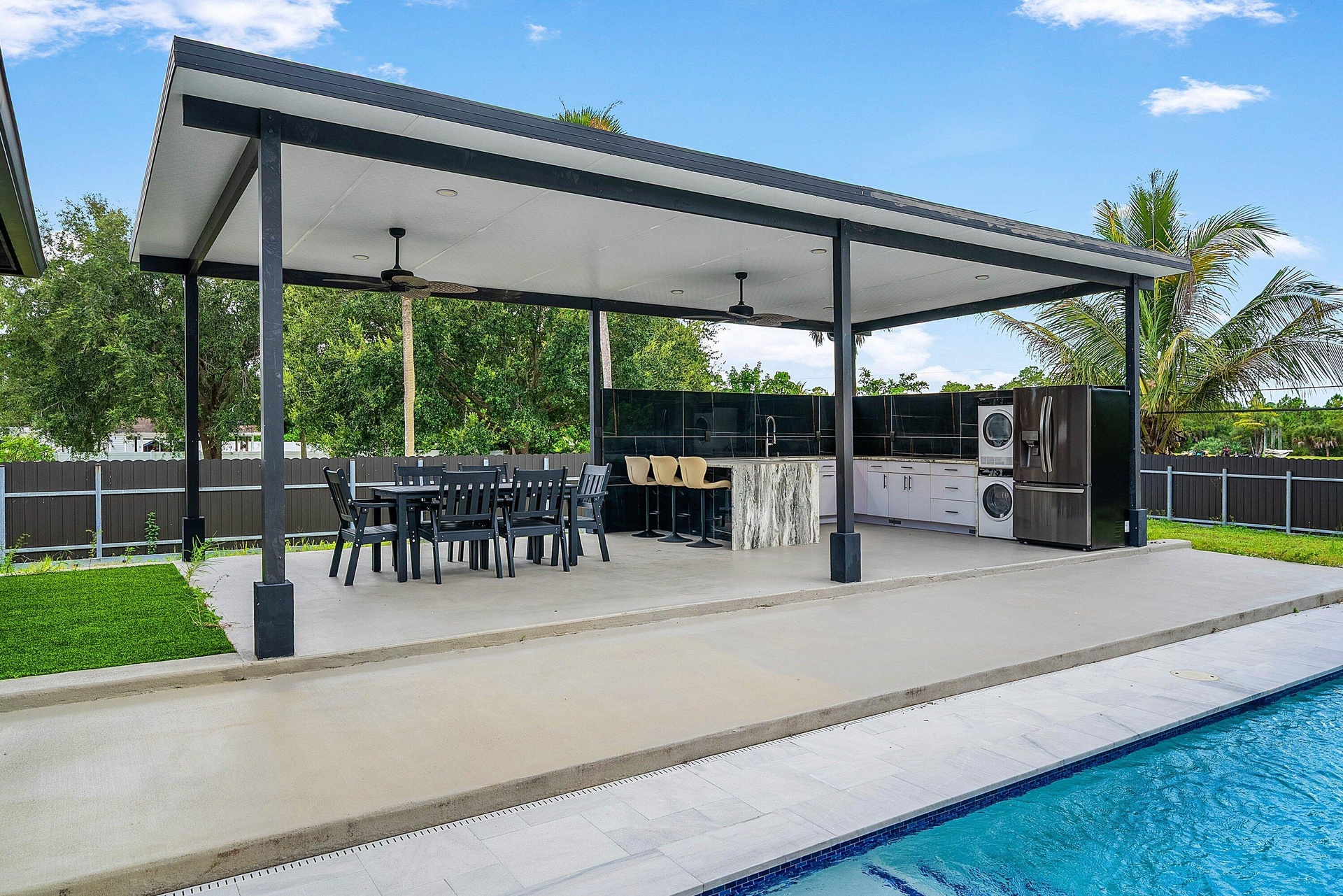 Covered outdoor kitchen featuring a built-in sink, ample counter space, and integrated appliances