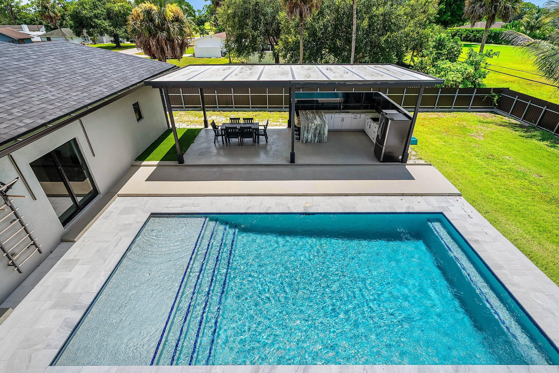 Rectangular swimming pool with integrated steps, surrounded by light-toned tile decking