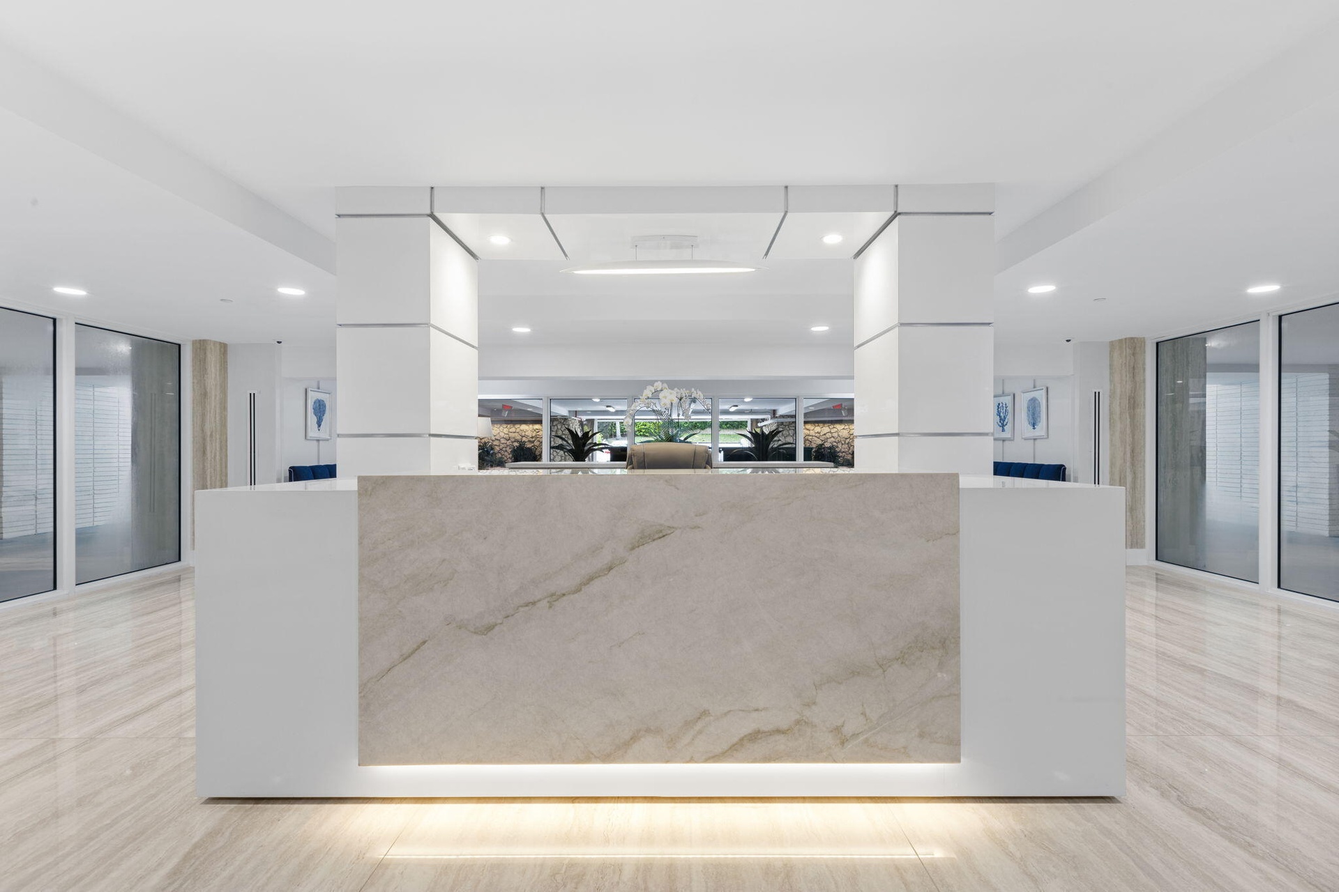 Lobby area featuring a stone-finish reception desk with integrated lighting, polished tile flooring, and recessed ceiling lighting