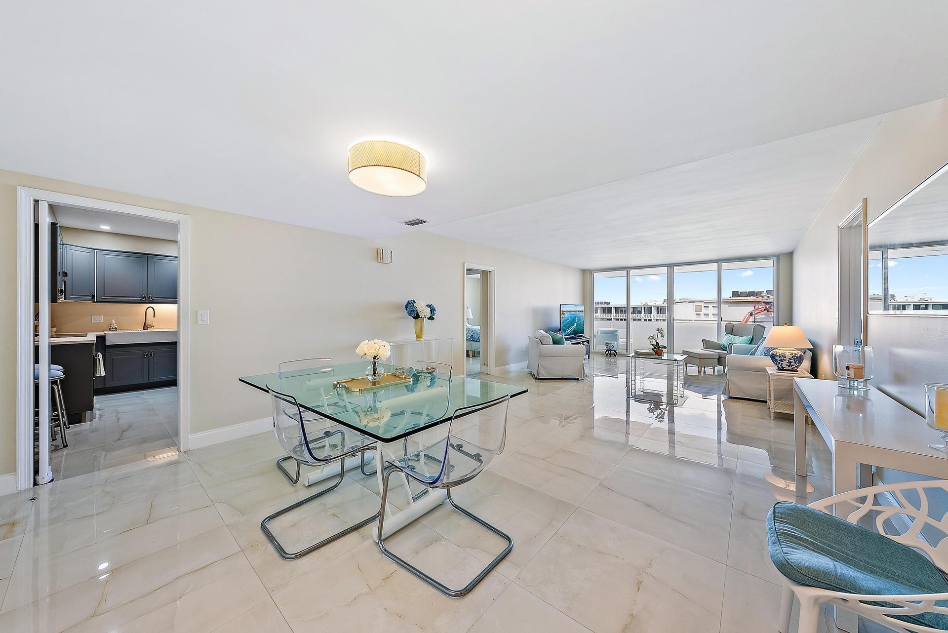Expansive open-concept living area showcasing polished light-stone flooring, floor-to-ceiling windows with panoramic outlooks, recessed ceiling lighti