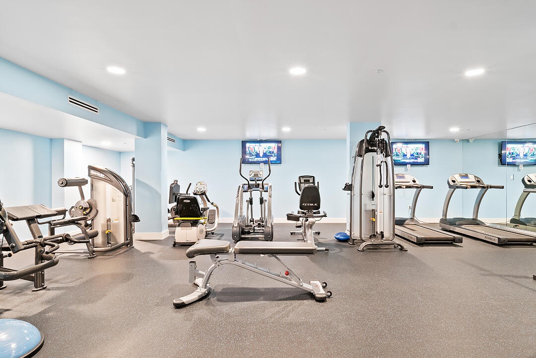 Fitness room featuring recessed lighting, light blue walls, and rubberized flooring