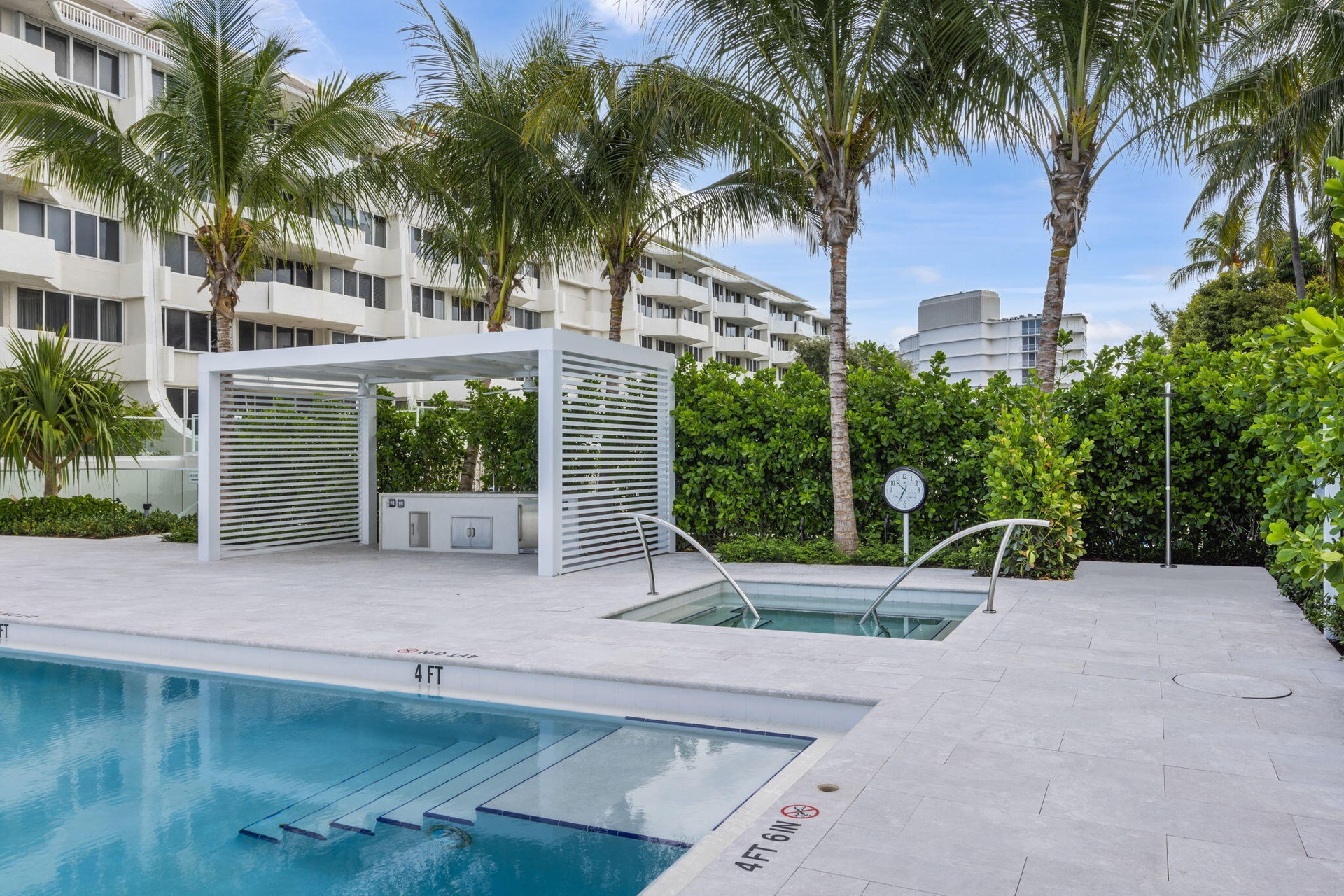 Swimming pool with integrated steps, adjacent spa, and surrounding light-toned paved deck