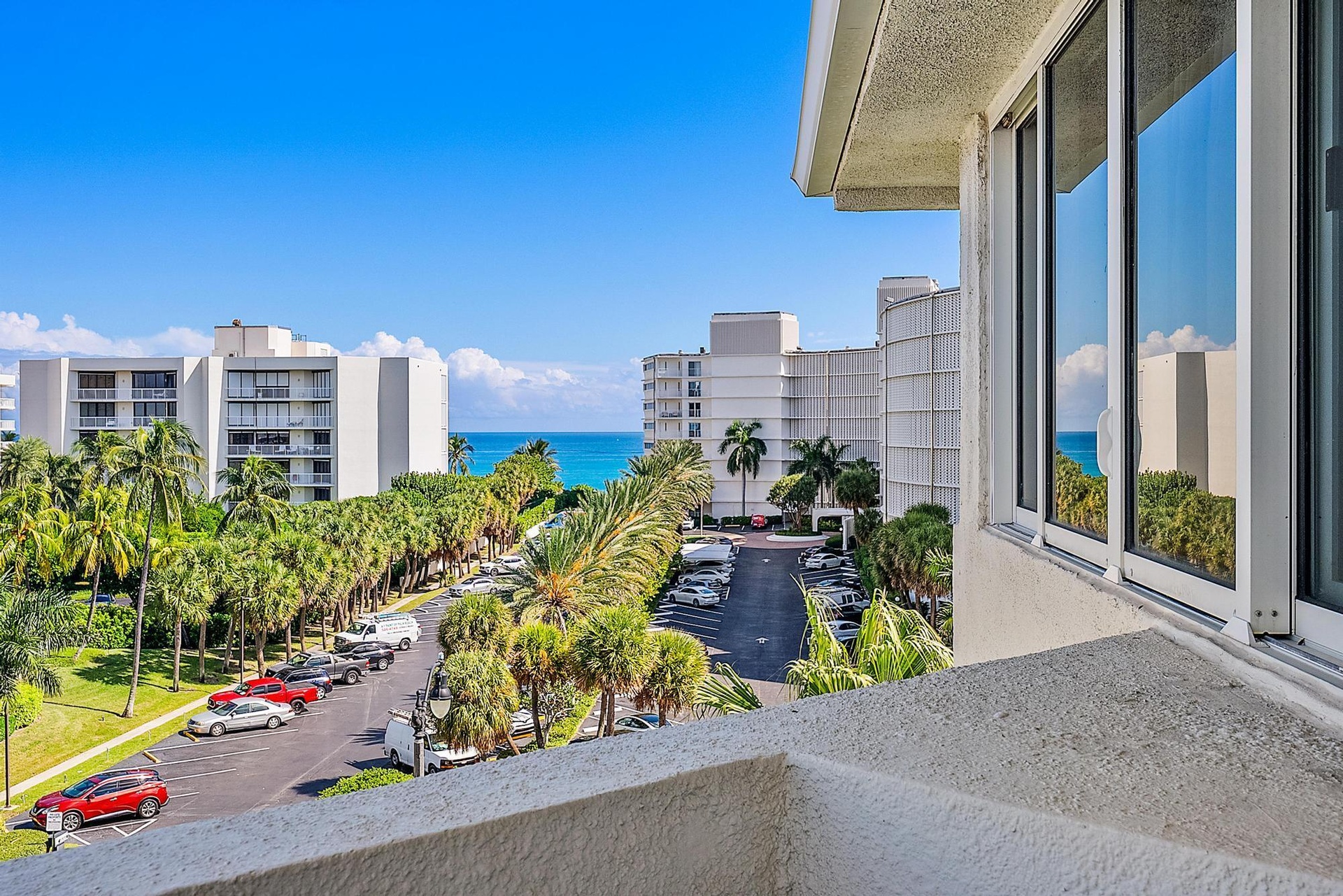 Expansive water body, lush palm trees, and clear blue sky visible from the property